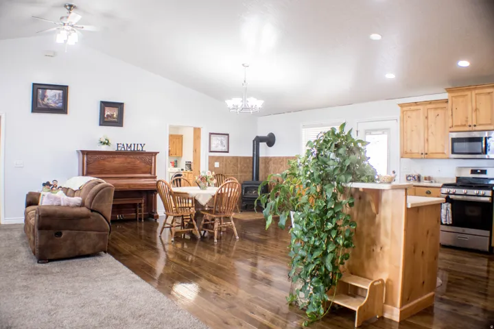 Kitchen featuring light countertops, a wood stove, stainless steel appliances, dark wood-type flooring, and light brown cabinetry