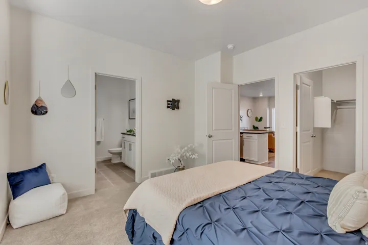 Bedroom featuring ensuite bathroom, a spacious closet, and light carpet