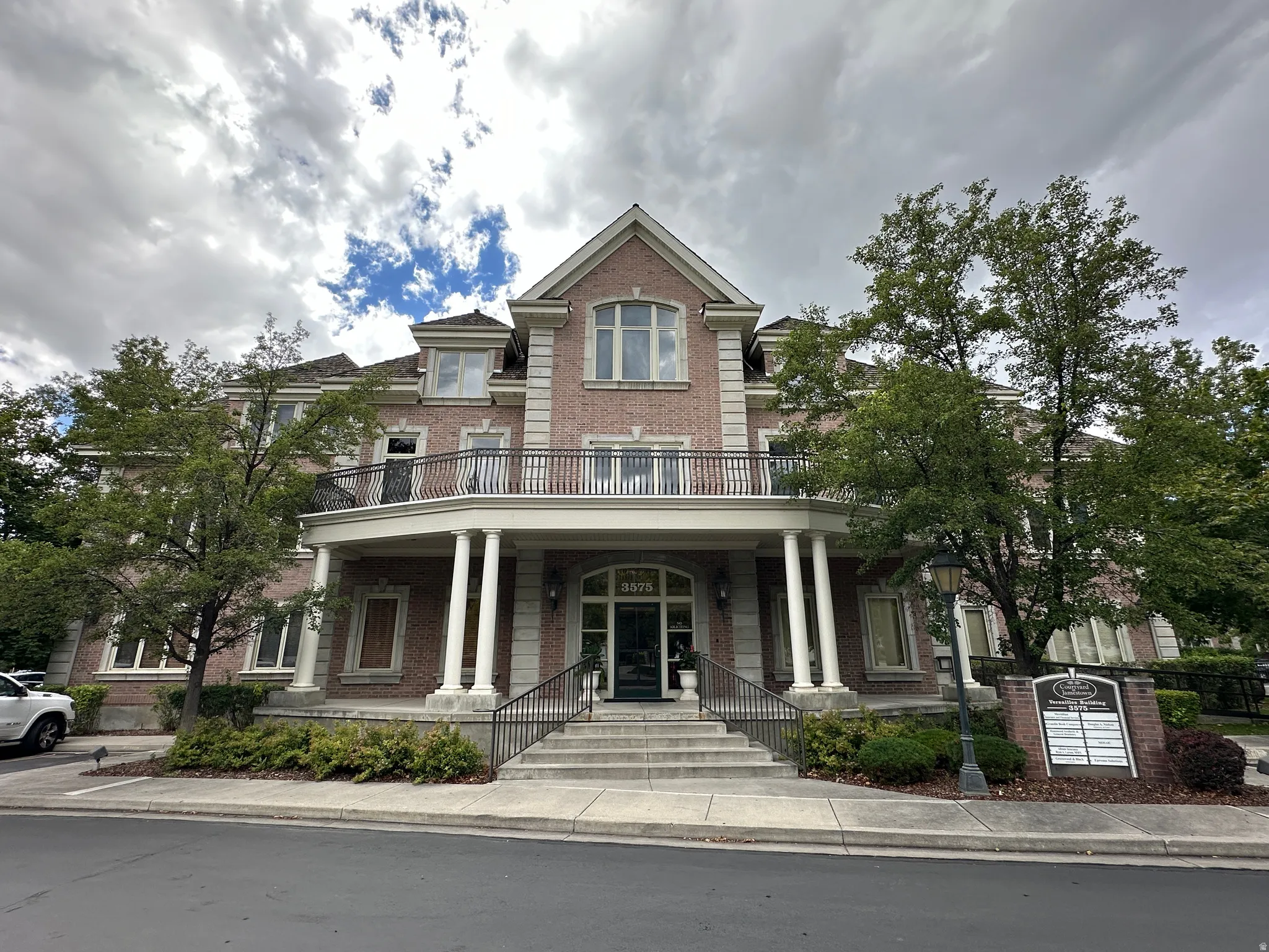 View of front of home featuring brick siding, a balcony, and covered porch