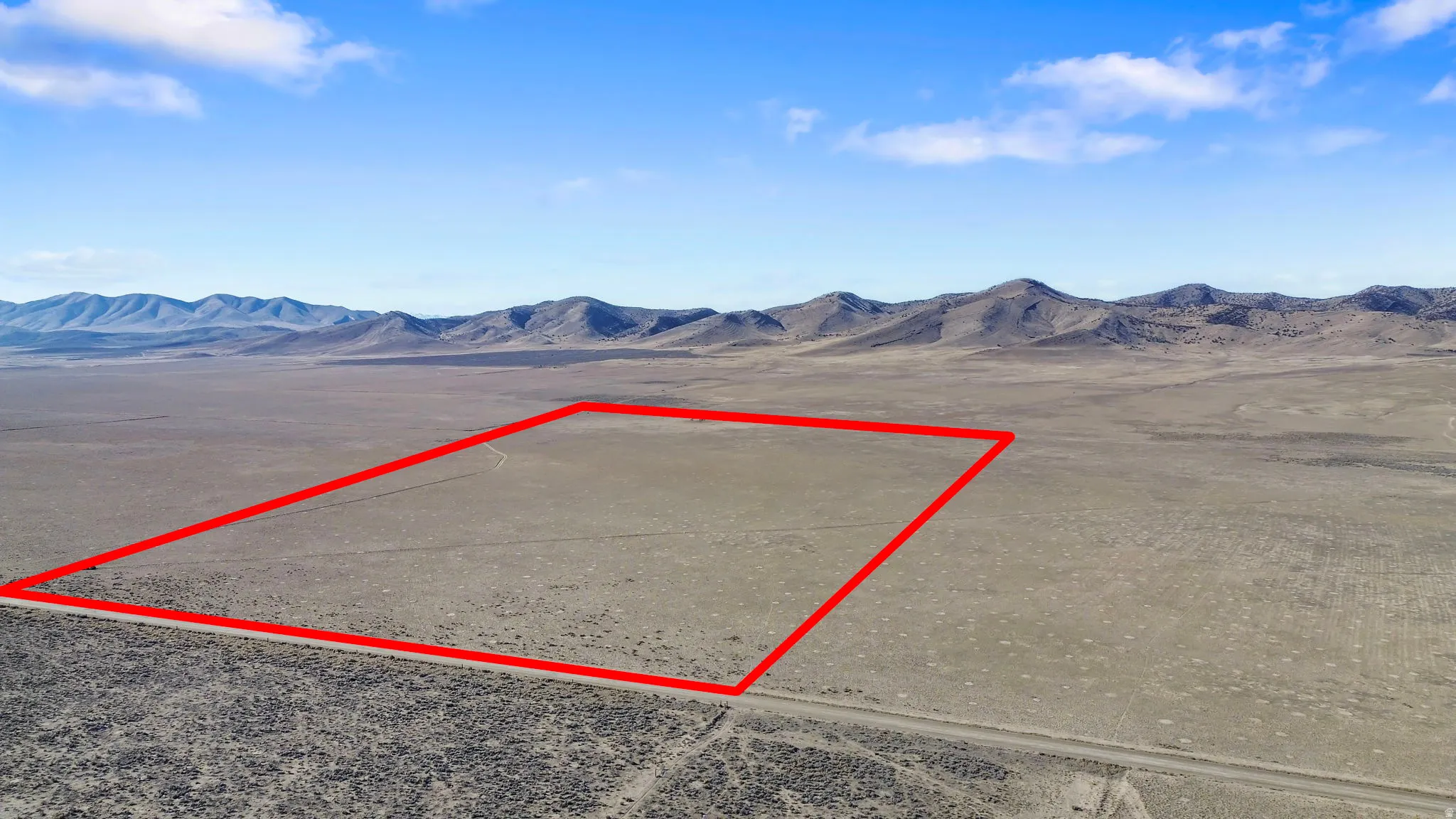 Aerial view of property and surrounding area featuring property boundaries highlighted and a mountainous background