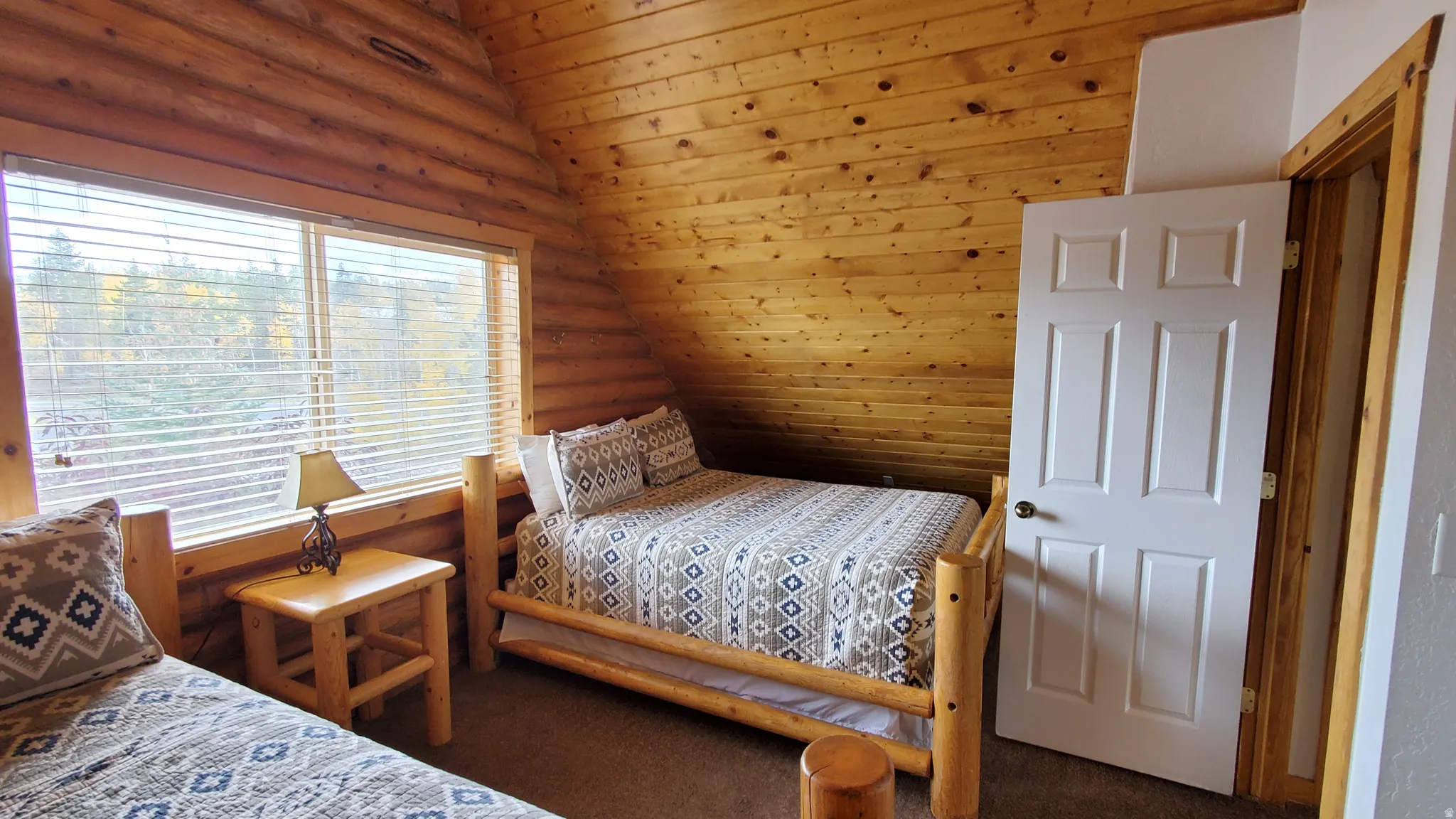 Carpeted bedroom with vaulted ceiling, wood ceiling, and log walls