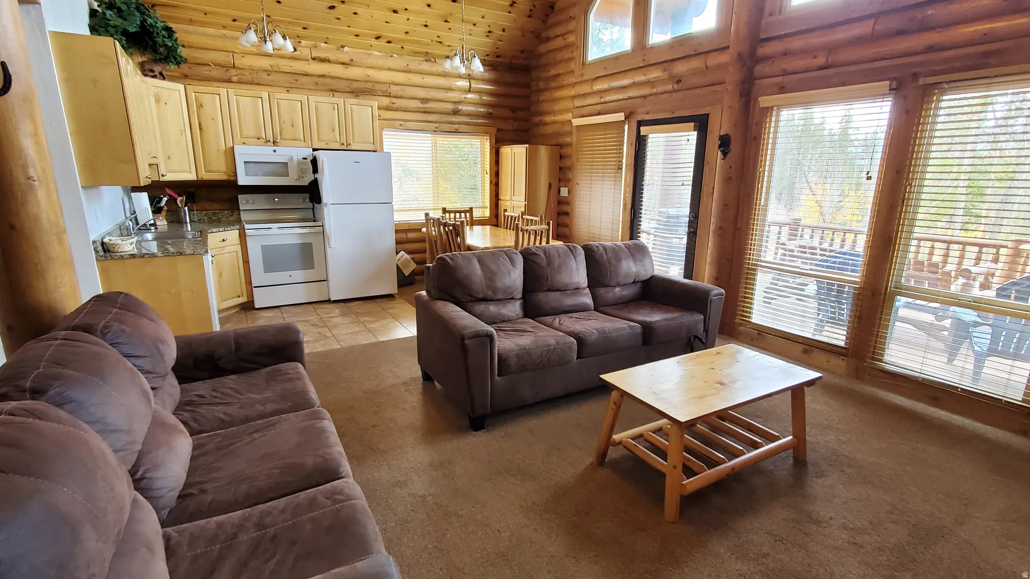Living area featuring log walls, light colored carpet, and a high ceiling