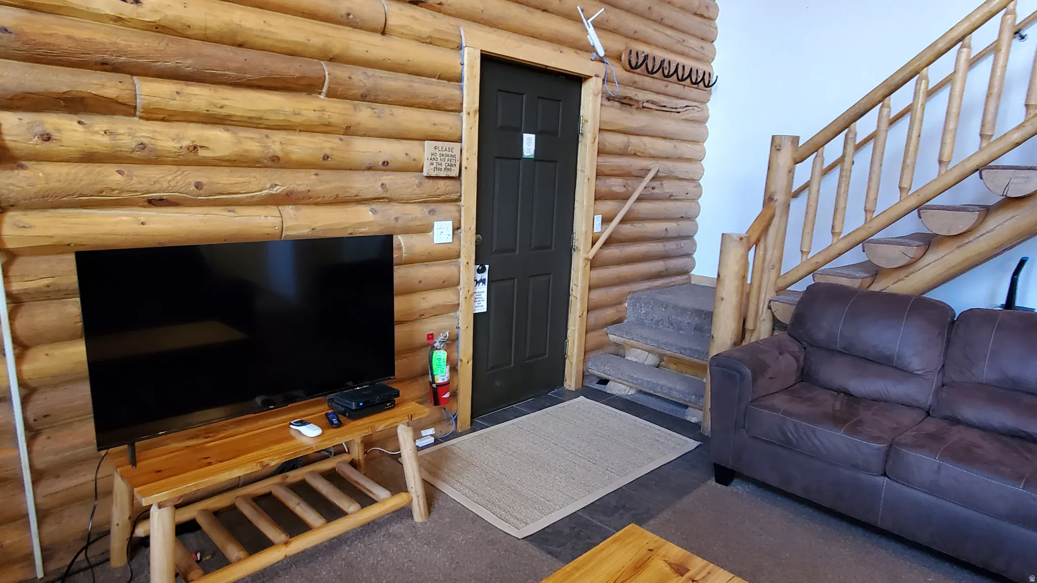 Living area with stairs, rustic walls, and carpet floors