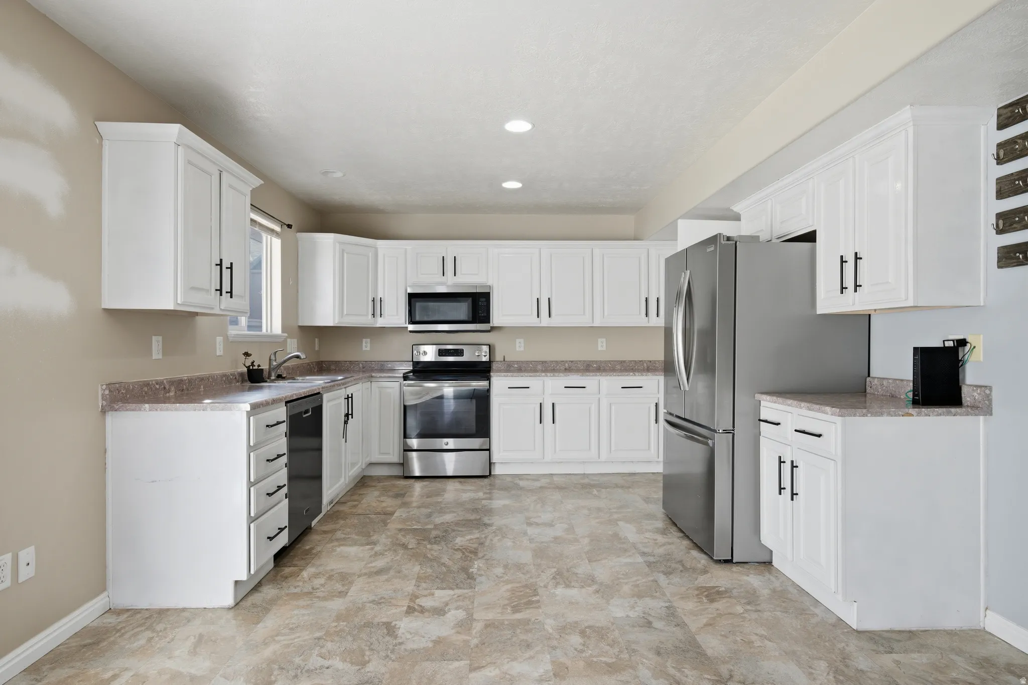 Kitchen featuring appliances with stainless steel finishes, white cabinetry, and light countertops