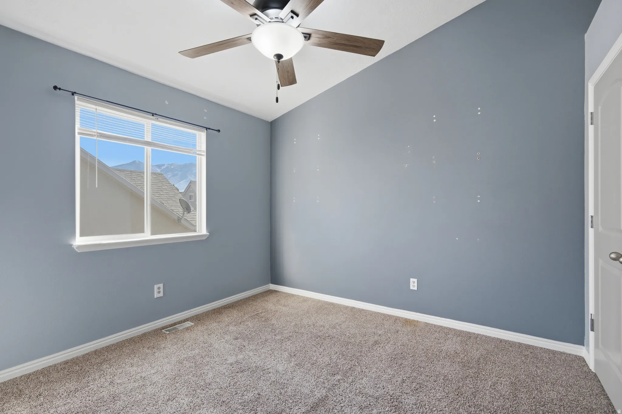 Carpeted bedroom featuring vaulted ceiling and ceiling fan