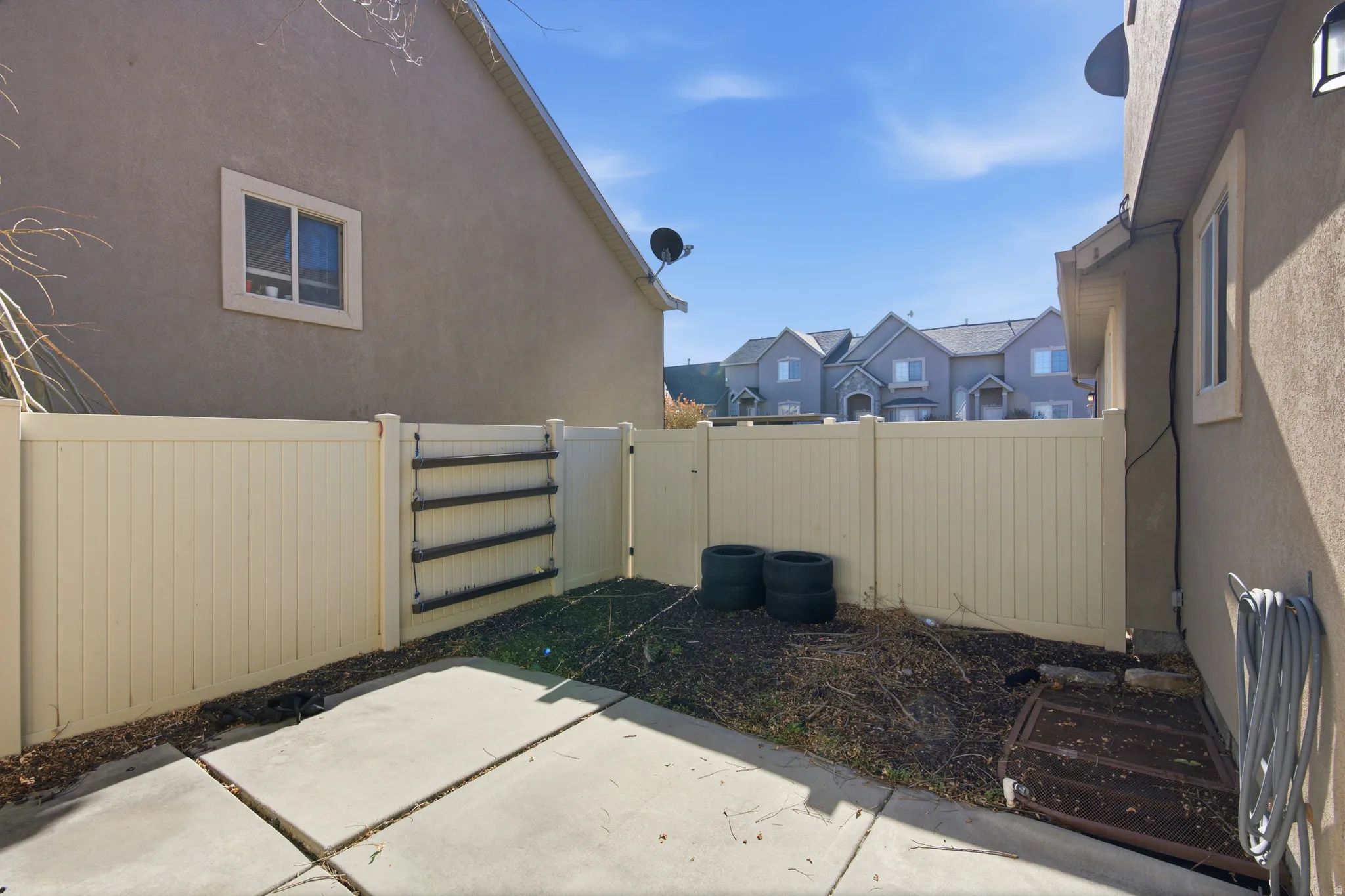 View of side of property with a gate, stucco siding, a fenced backyard, a patio area, and a residential view
