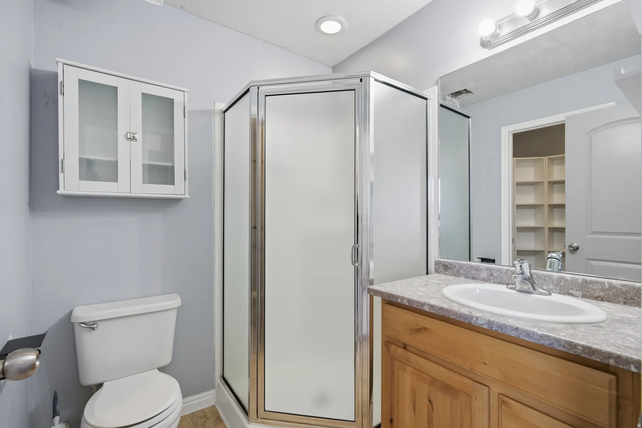 Full bath with vanity, a shower stall, and a walk in closet