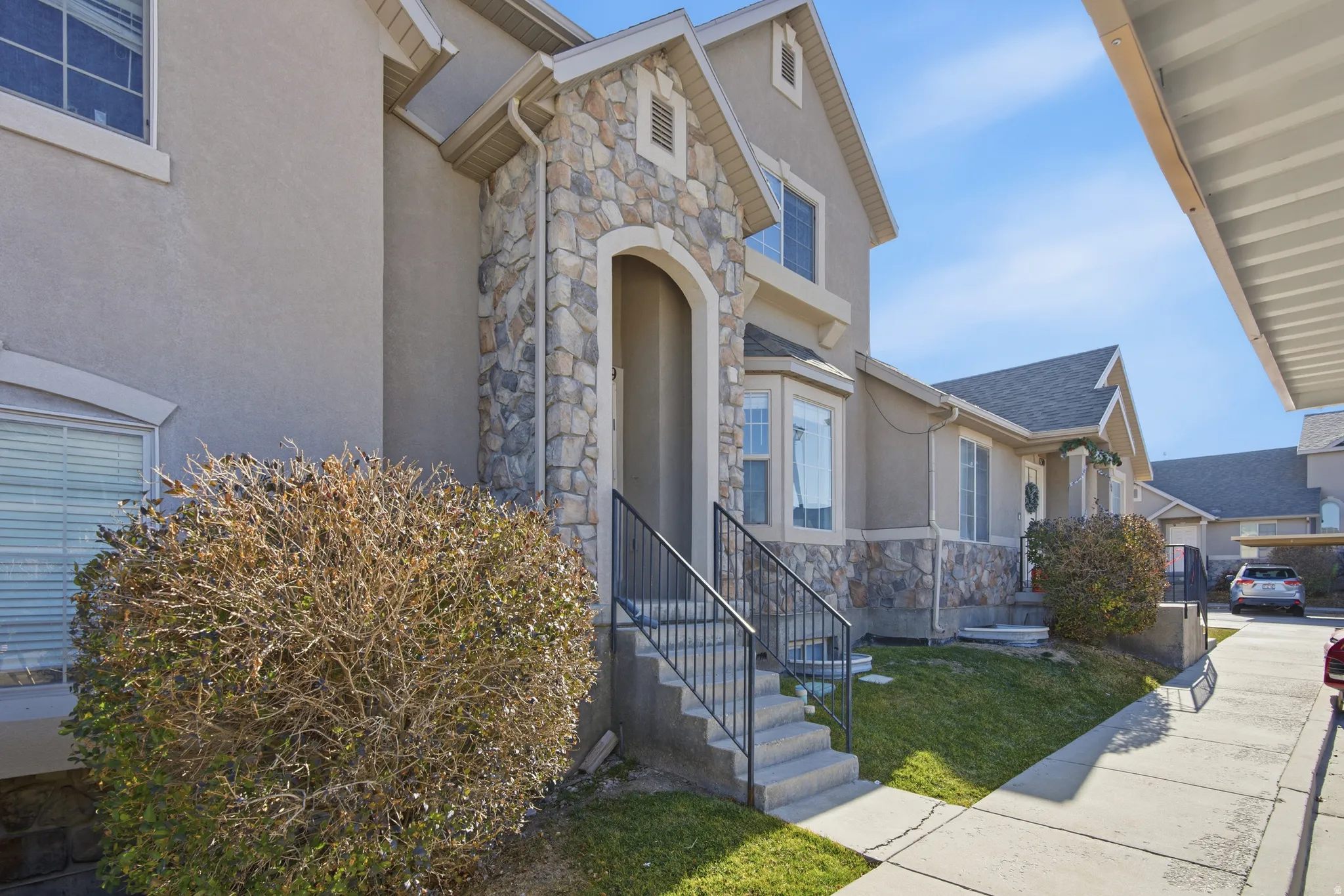 Property entrance with stone siding, stucco siding, and a lawn