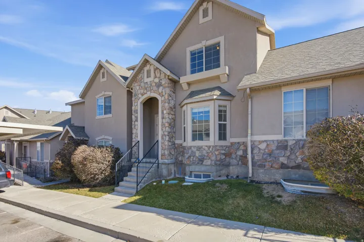 View of front of house with stone siding, stucco siding, roof with shingles, and a front yard