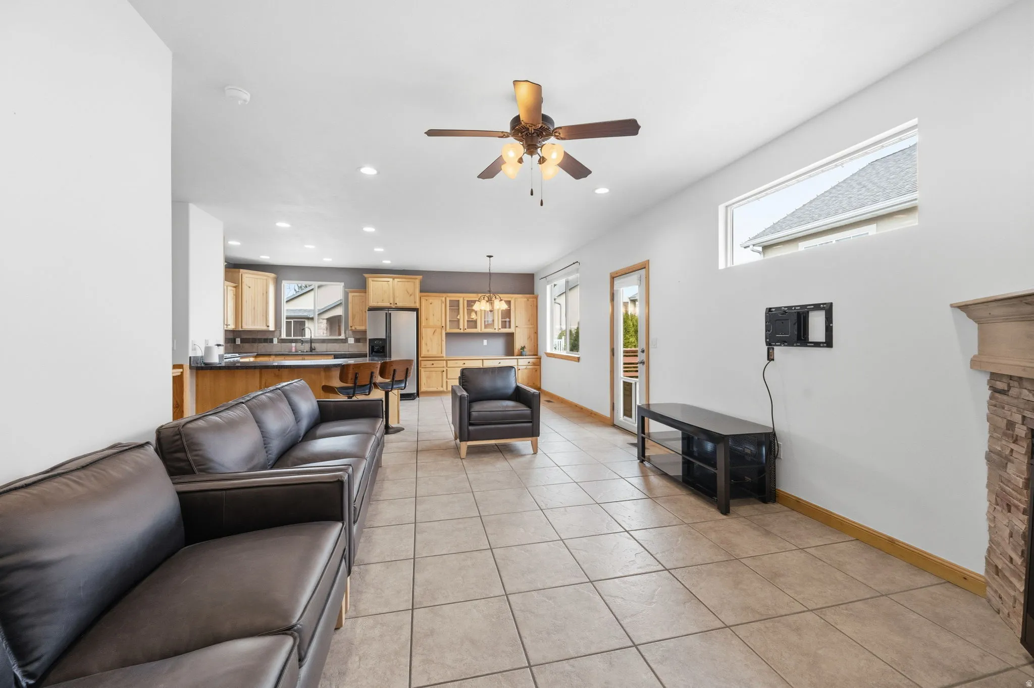 Living room with light tile patterned floors, recessed lighting, a ceiling fan, and a chandelier