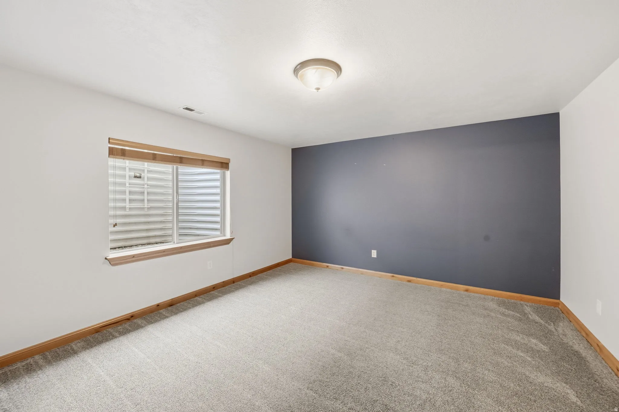 Carpeted spare room featuring baseboards