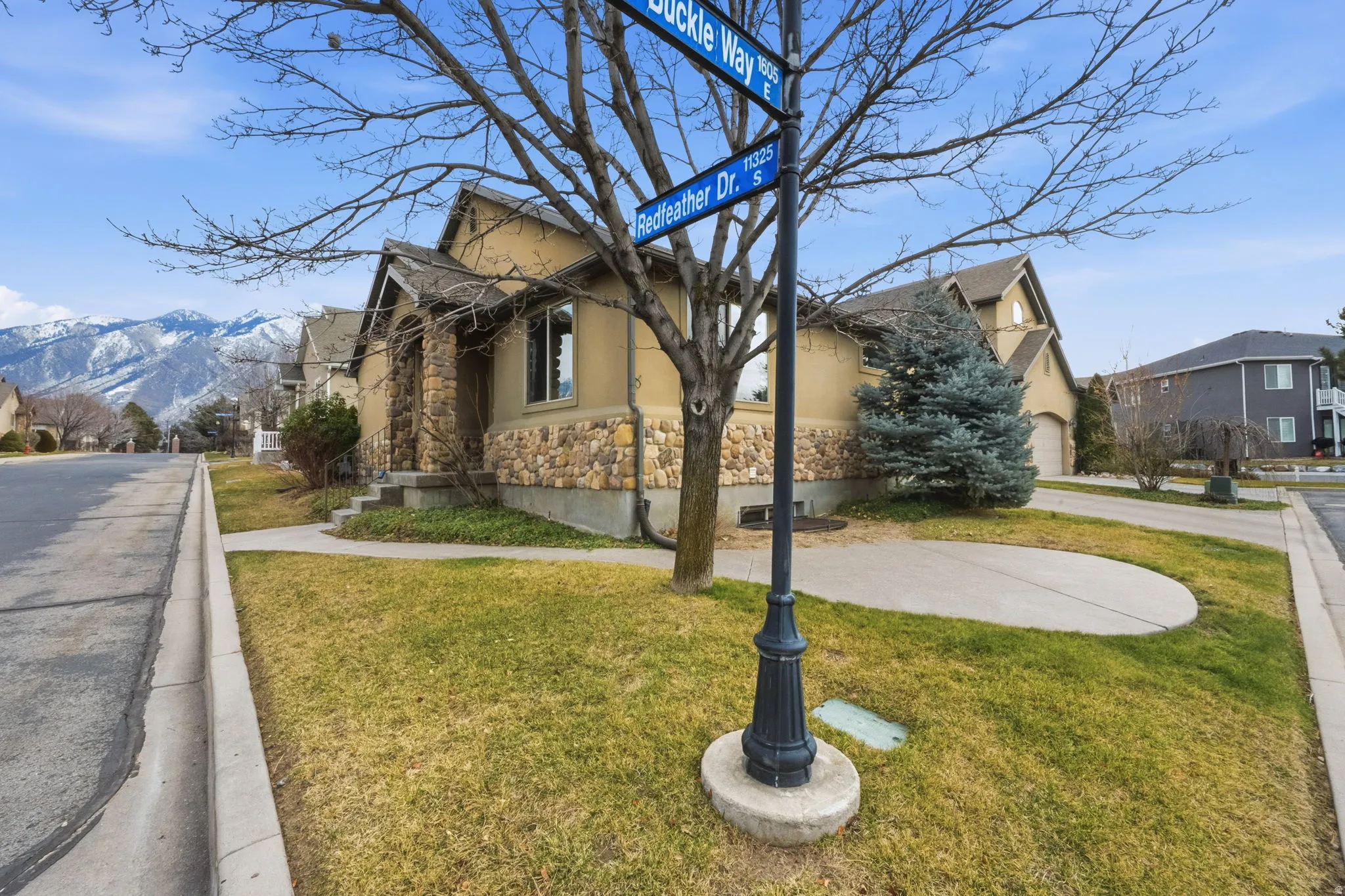 View of property exterior featuring stucco siding, stone siding, a lawn, and a residential view