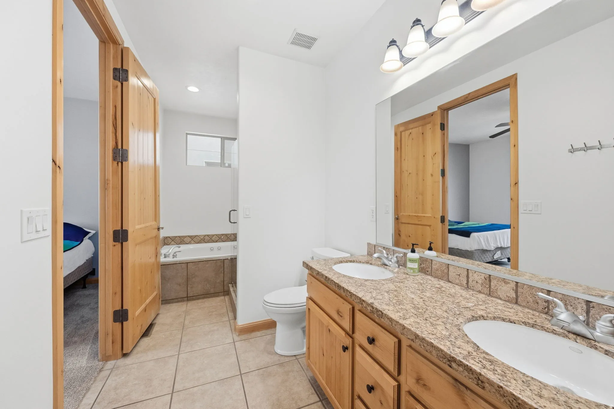 Full bath with connected bathroom, a garden tub, double vanity, and light tile patterned flooring