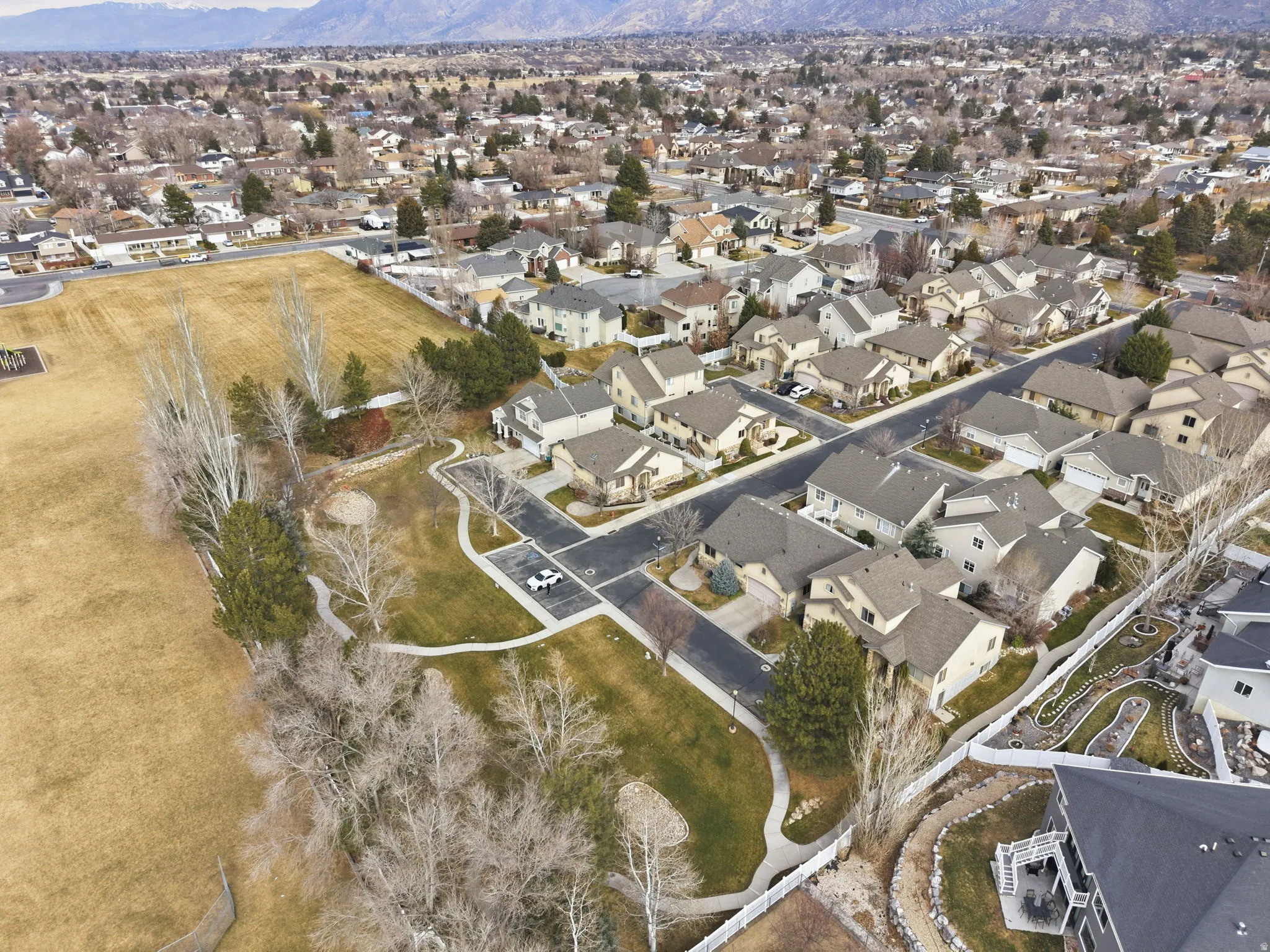 Aerial view of property and surrounding area featuring nearby suburban area and a mountain backdrop