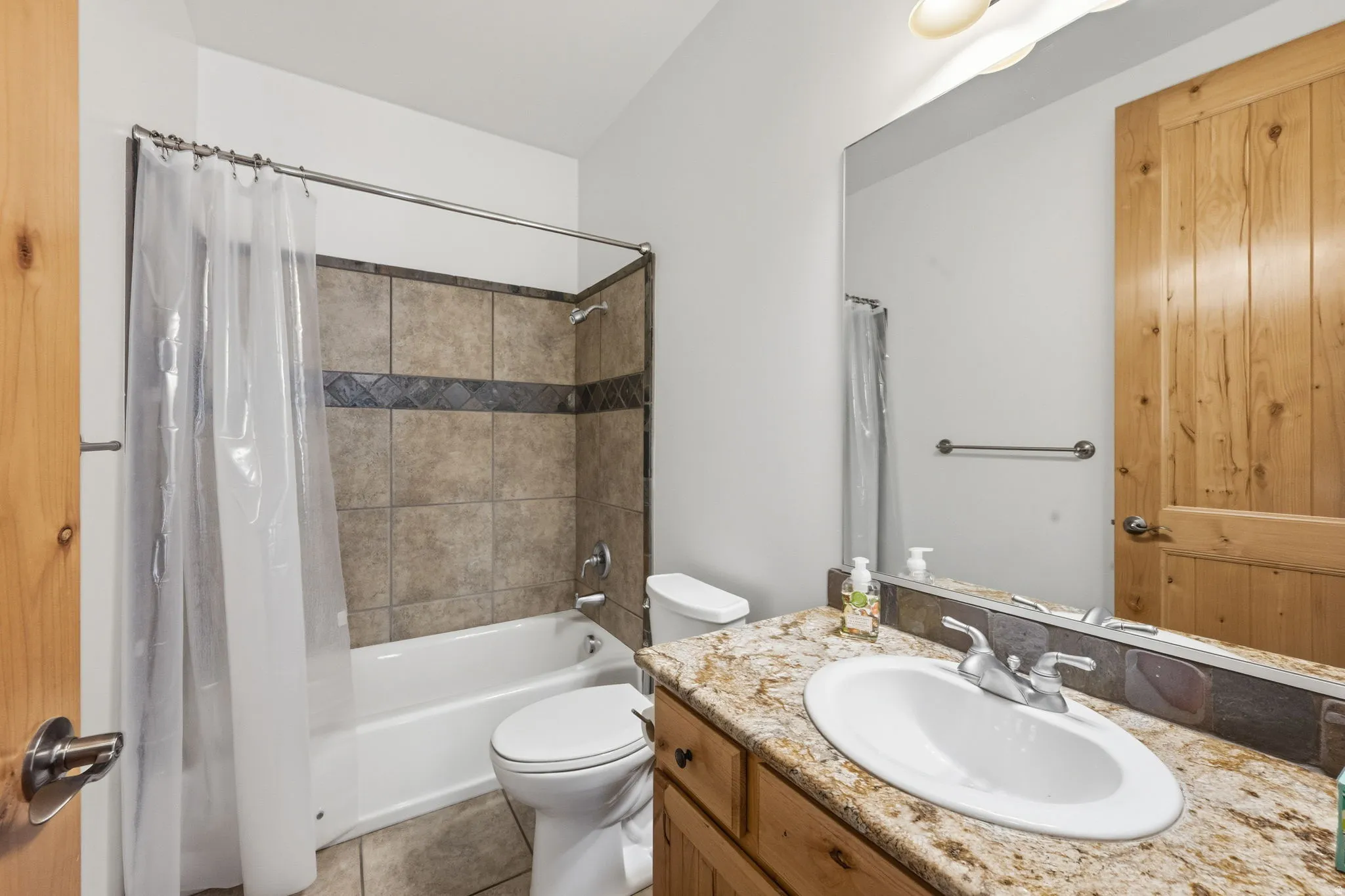 Full bathroom with shower / bath combo, vanity, and light tile patterned flooring