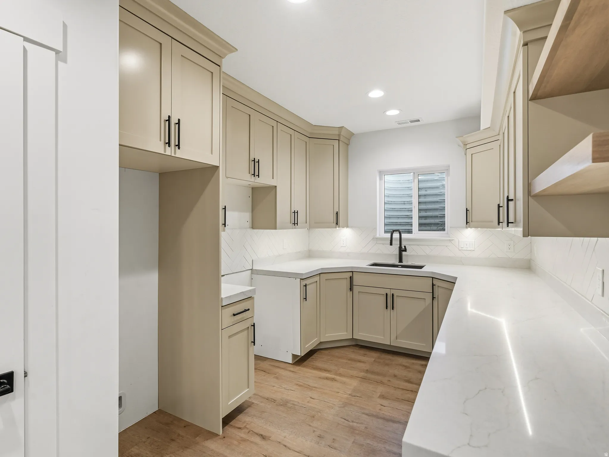 Kitchen with cream cabinetry, light wood-style floors, tasteful backsplash, light stone countertops, and recessed lighting