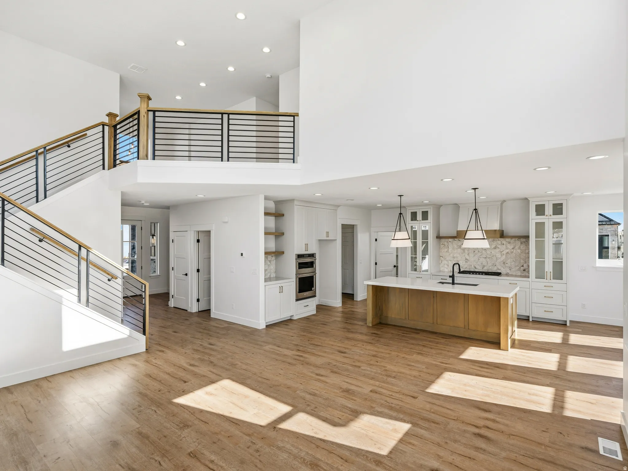 Unfurnished living room featuring light wood-style flooring, a high ceiling, recessed lighting, and plenty of natural light
