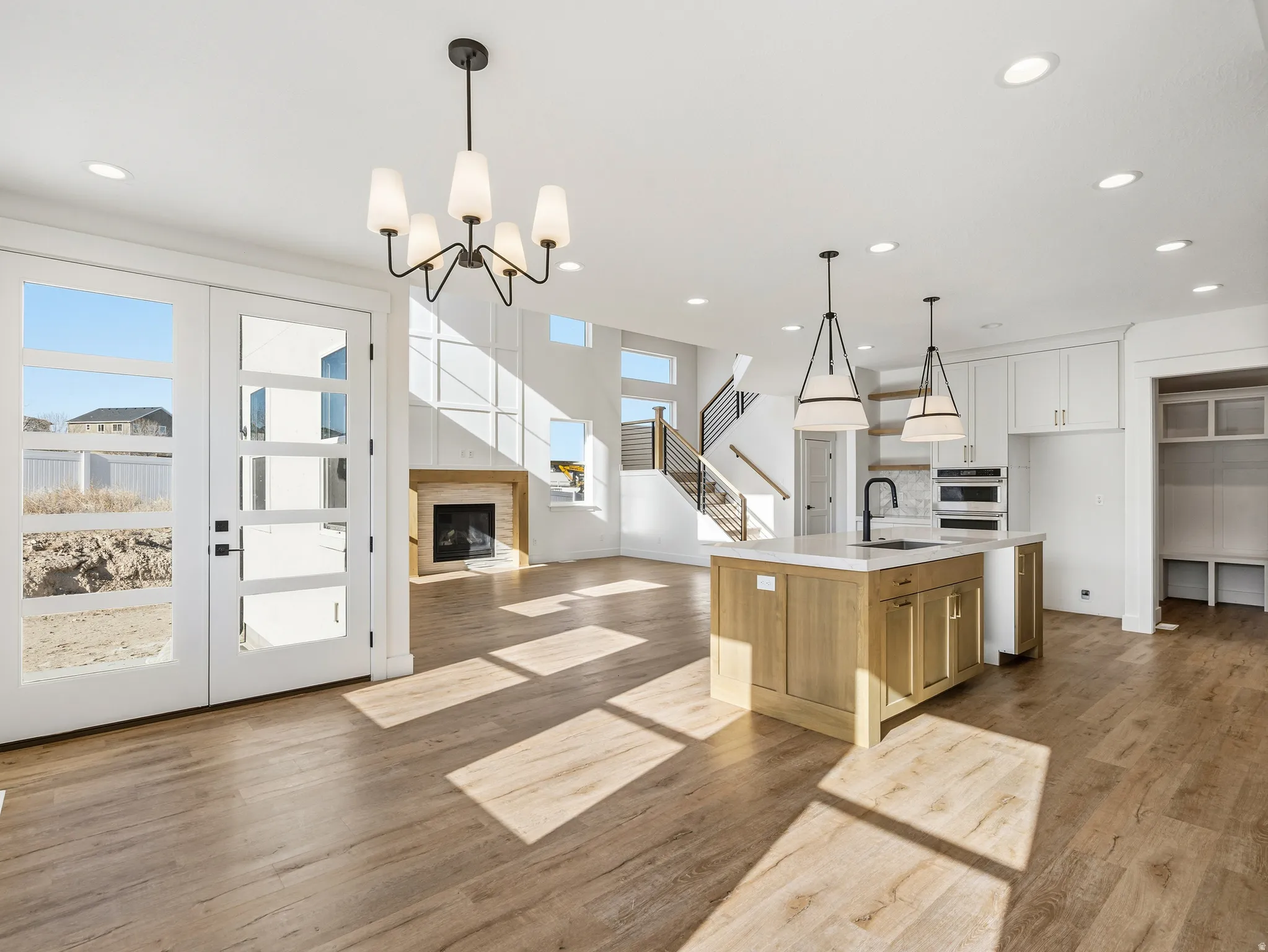 Dual tone kitchen with a brick fireplace, light wood-style floors, a center island with sink, and dual tone cabinetry