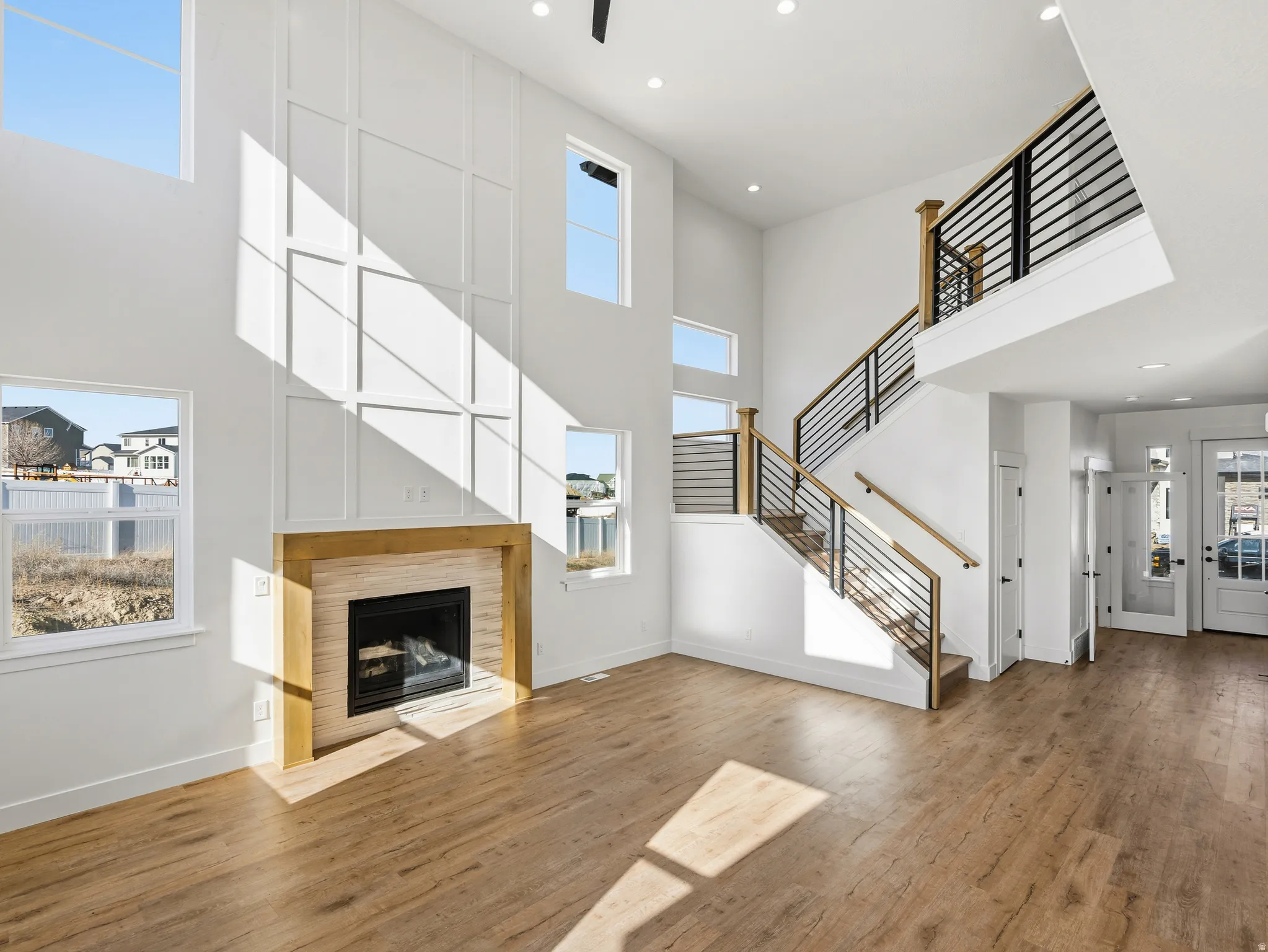 Unfurnished living room featuring a high ceiling, a tile fireplace, wood finished floors, and recessed lighting