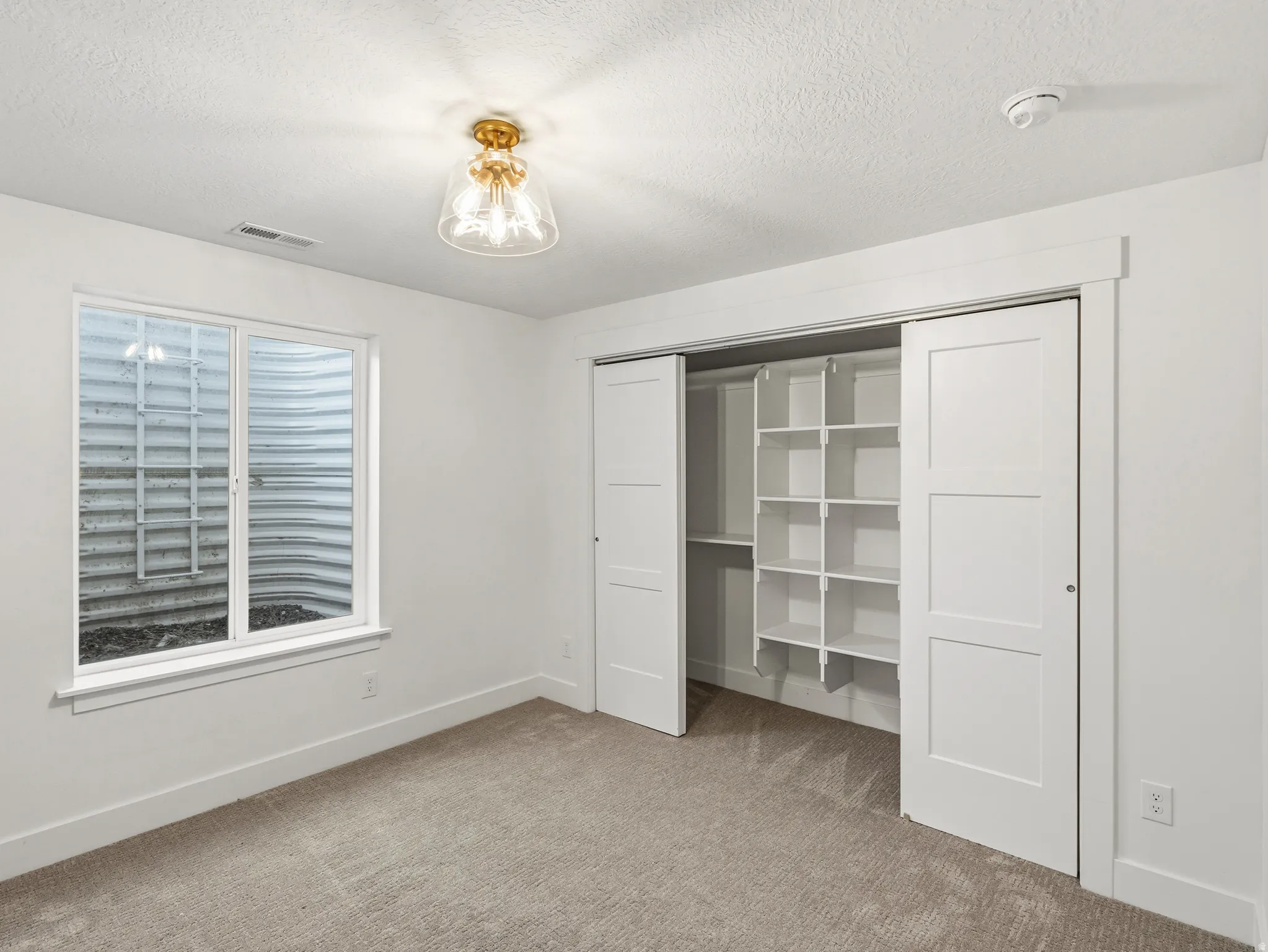 Unfurnished bedroom featuring light colored carpet, a textured ceiling, and a closet