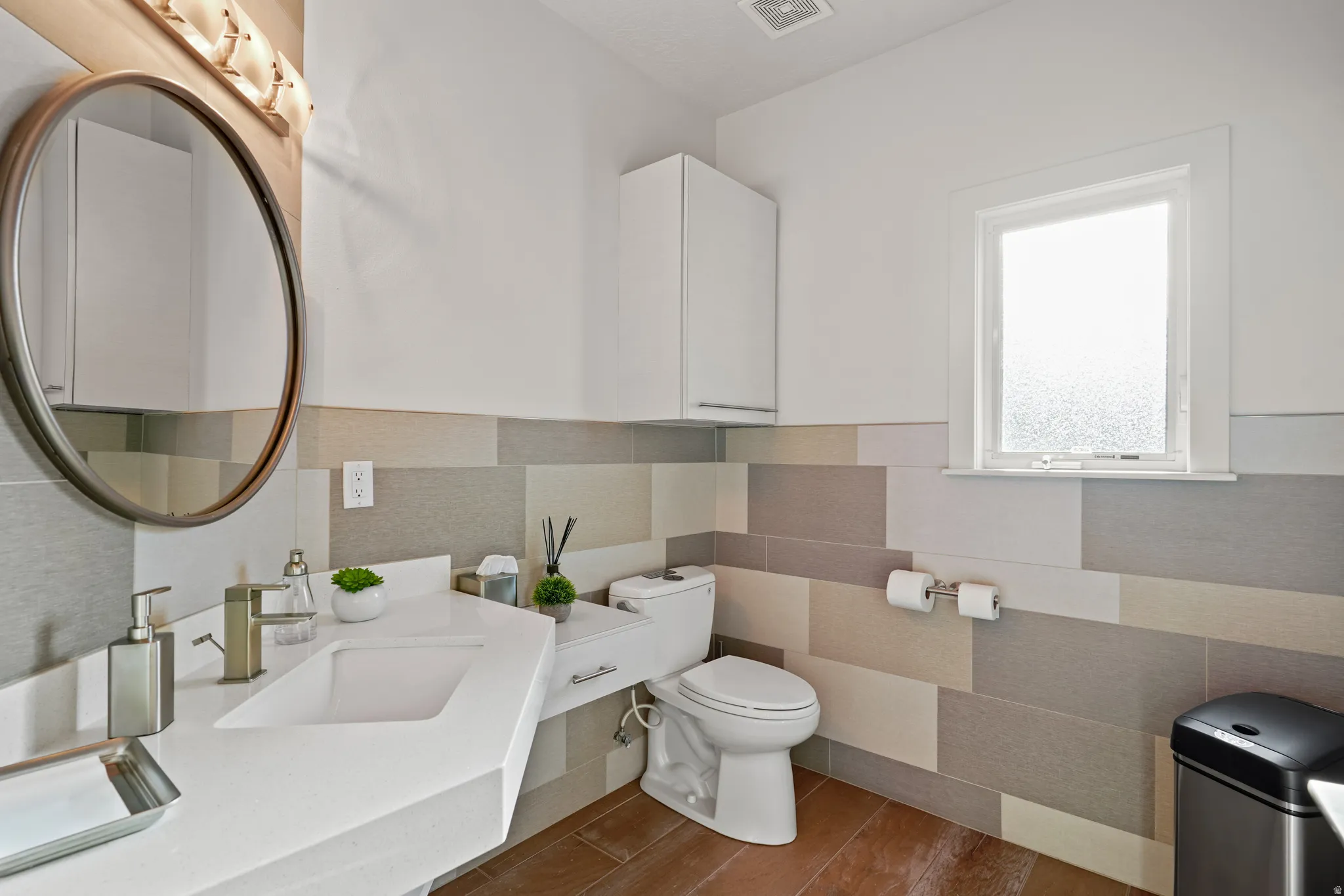 Bathroom featuring wood finished floors, tile walls, and vanity
