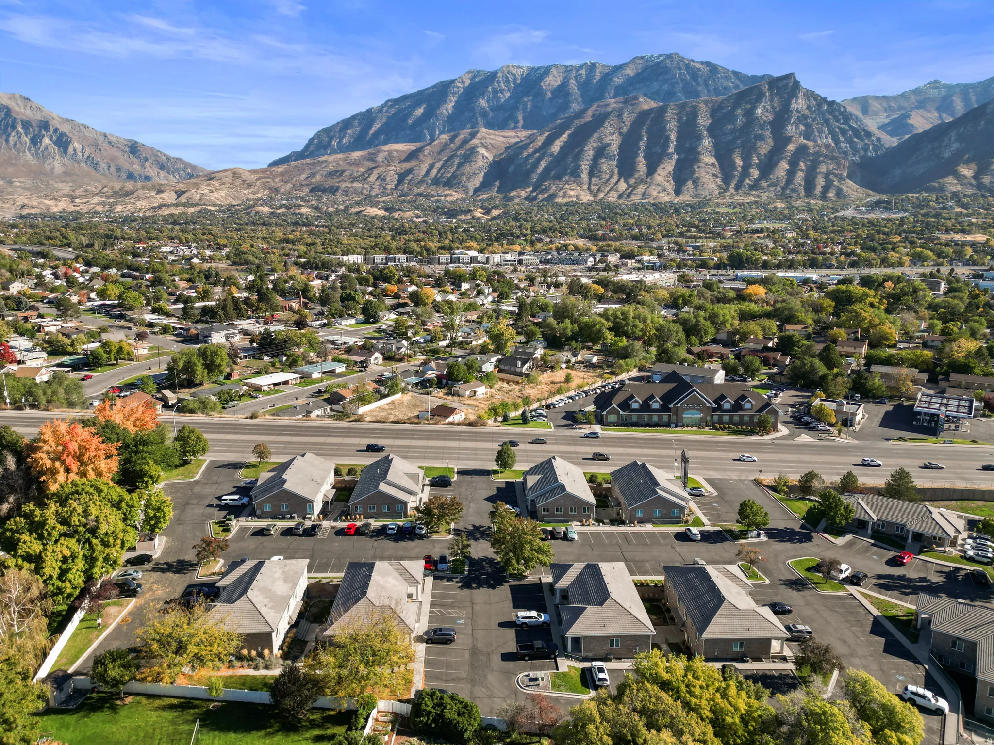 Aerial view of property and surrounding area featuring nearby suburban area and a mountain backdrop