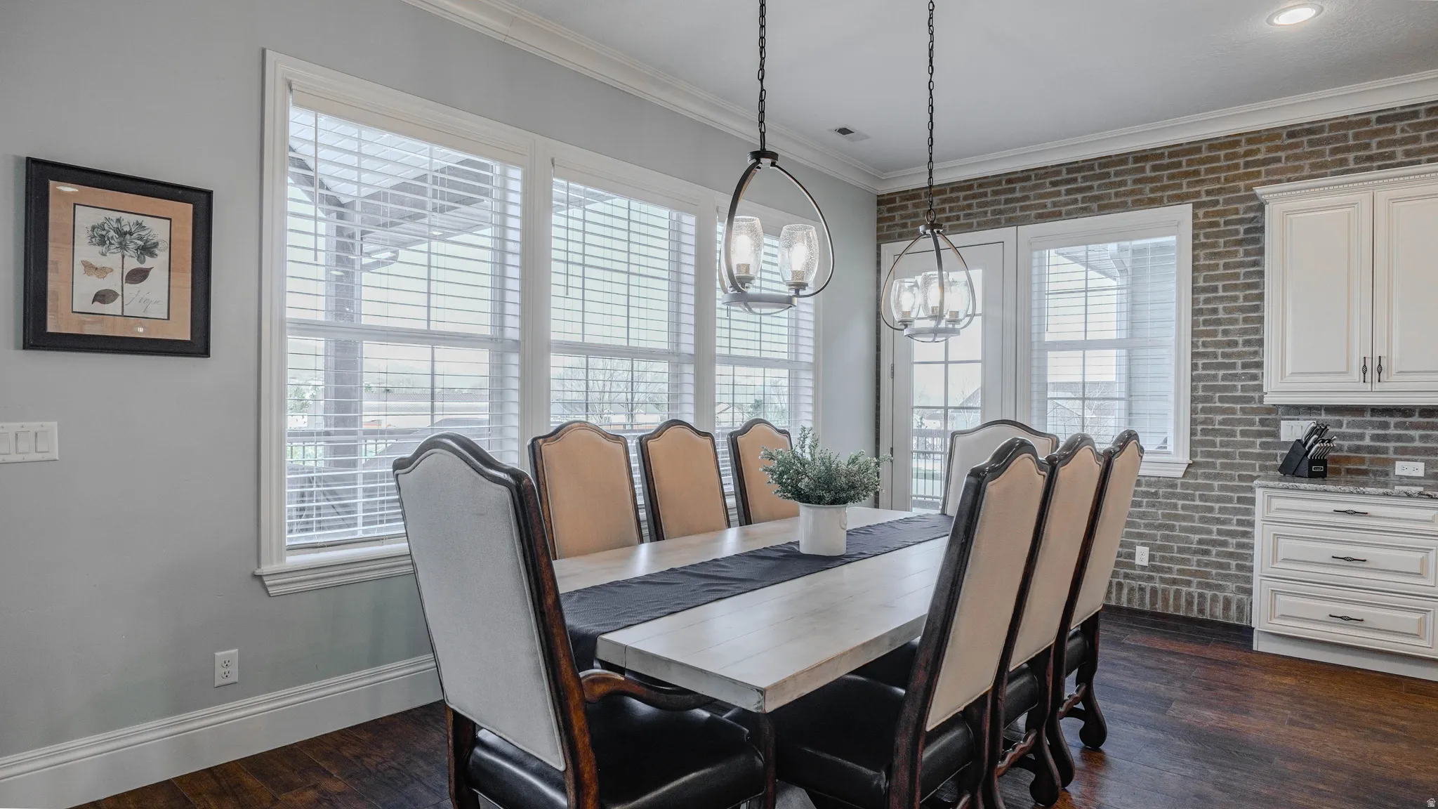 Dining area with crown molding, dark wood finished floors, brick wall, and a chandelier
