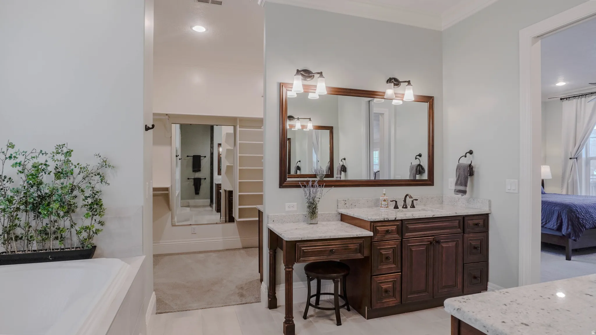 Ensuite bathroom with a spacious closet, vanity, a bath, recessed lighting, and ornamental molding