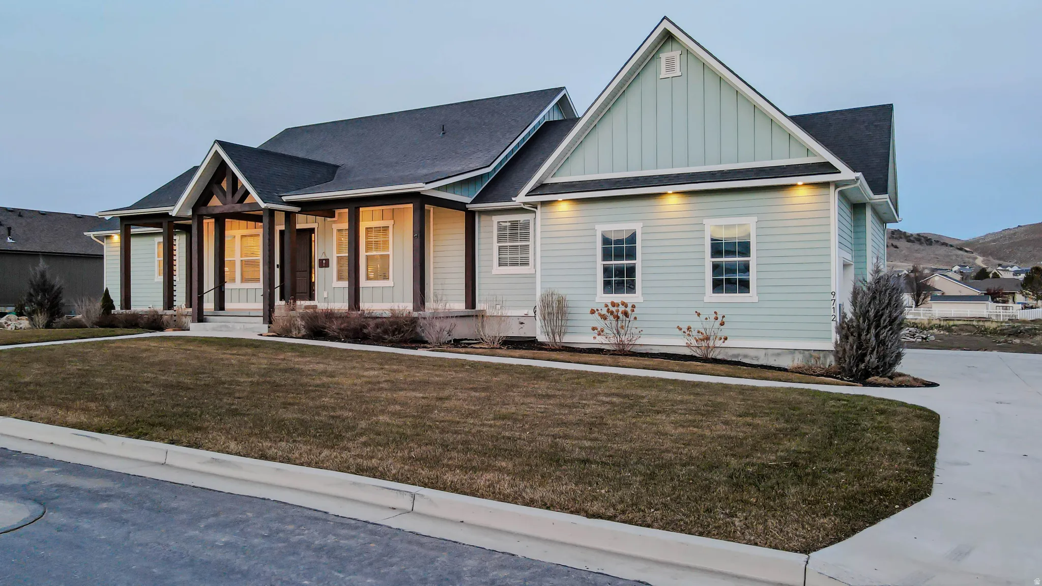 View of front of property featuring board and batten siding, covered porch, a front lawn, and a shingled roof
