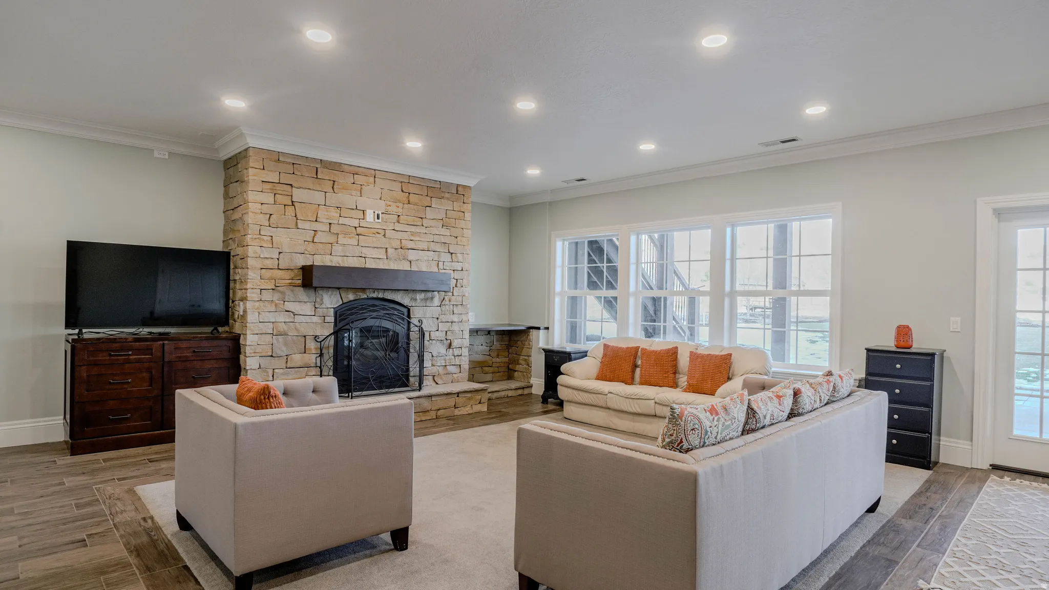 Living room with wood tiled floors, a fireplace, crown molding, and recessed lighting