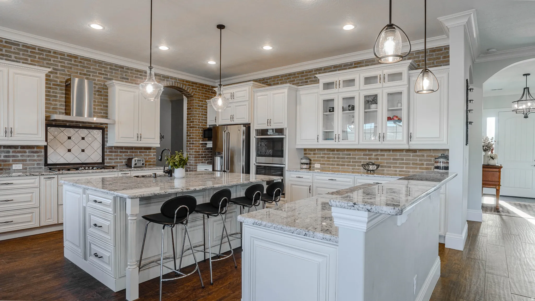 Kitchen featuring an island with sink, a kitchen breakfast bar, arched walkways, glass insert cabinets, and crown molding