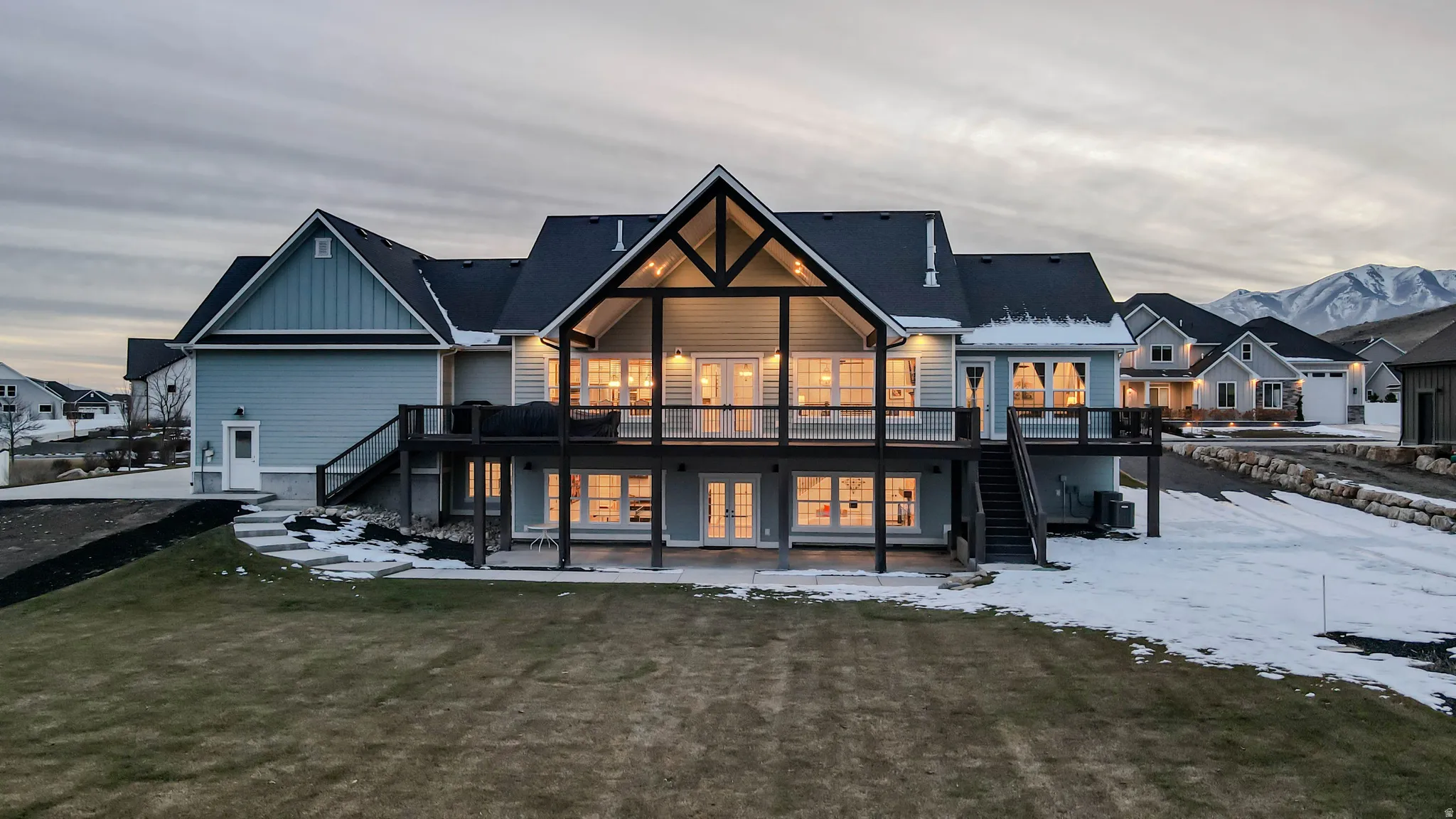 Snow covered property with stairs, a wooden deck, board and batten siding, and a patio