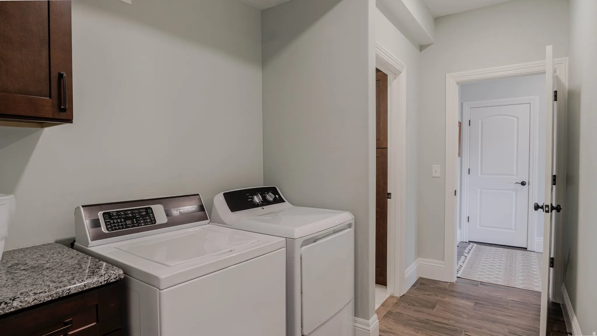 Laundry room with cabinet space, wood finished floors, and washer and clothes dryer