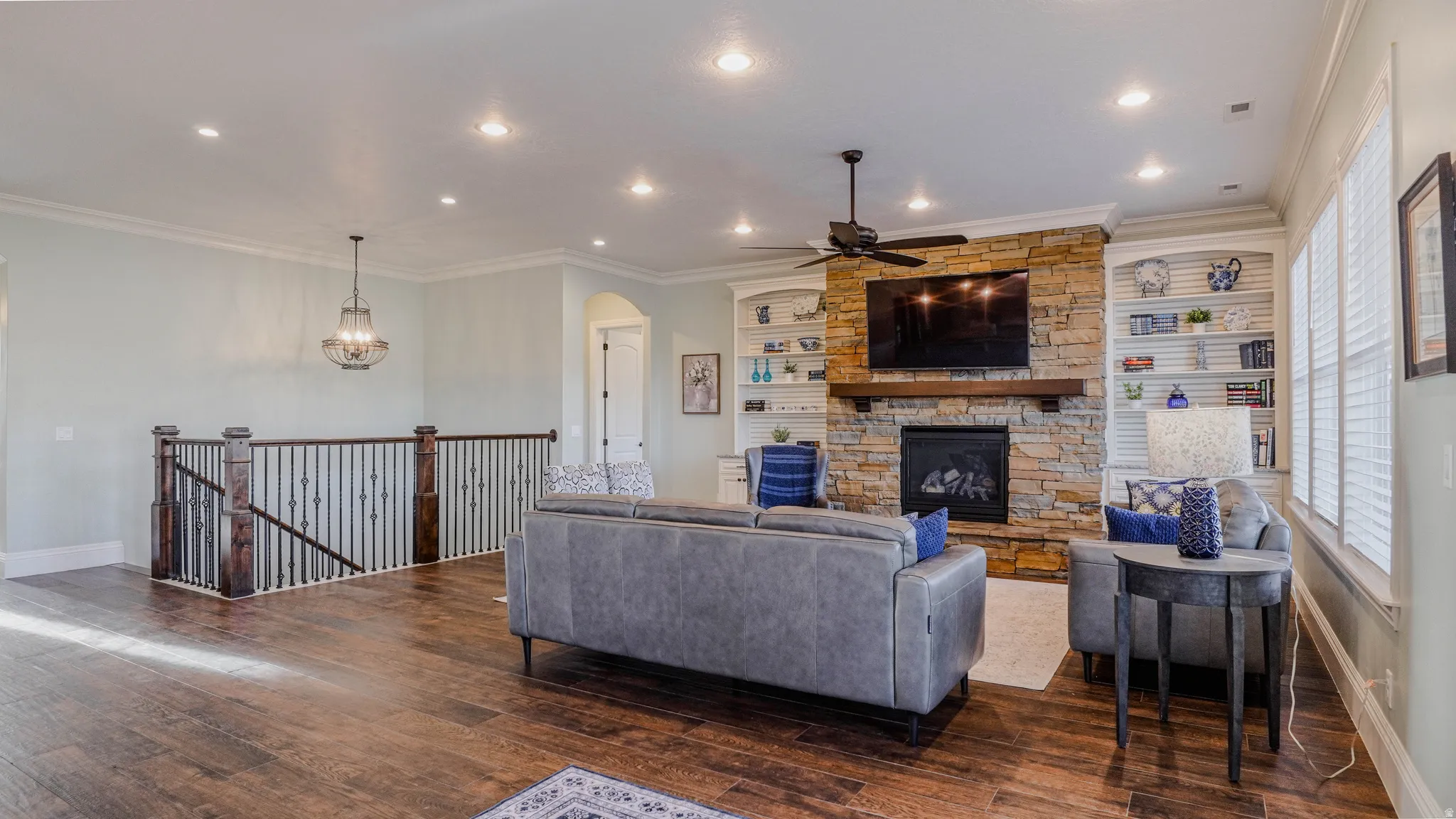 Living area featuring ornamental molding, a fireplace, wood-type flooring, ceiling fan, and recessed lighting