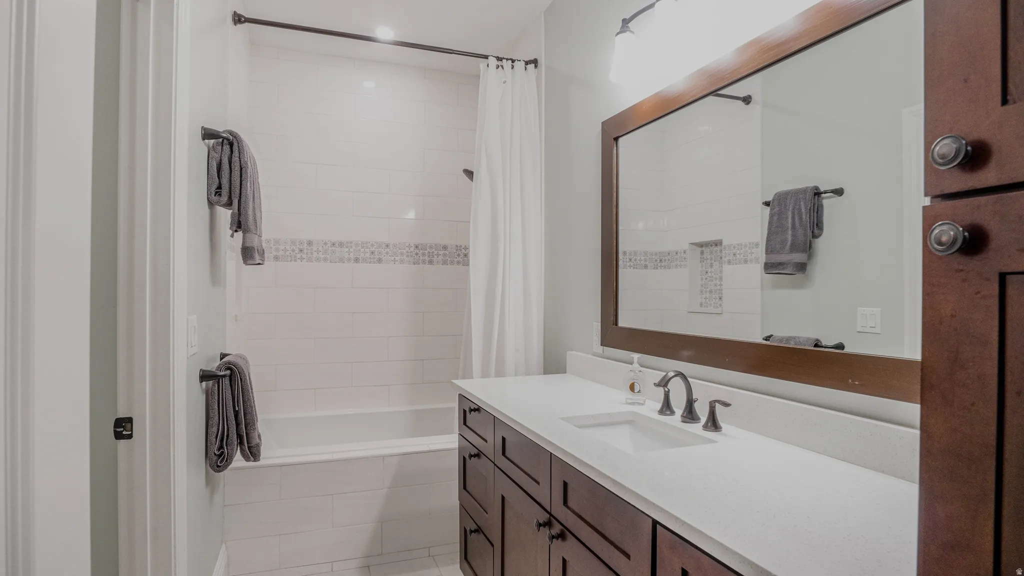 Full bathroom with tiled shower / bath combo and vanity