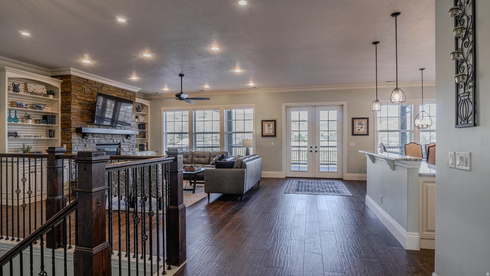Living room featuring french doors, ornamental molding, dark wood-style flooring, ceiling fan, and a fireplace