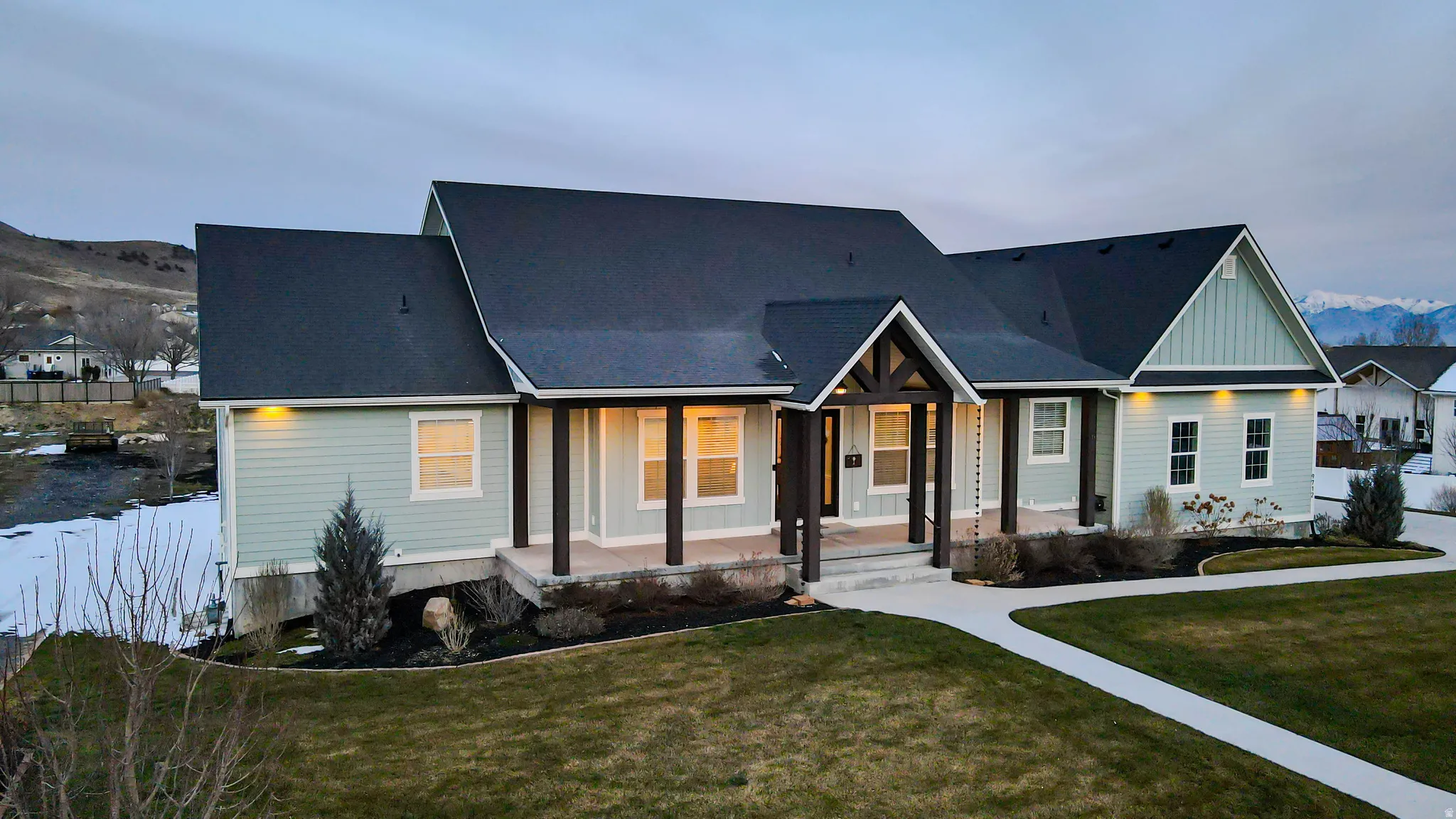 View of front facade with a mountain view, covered porch, a front yard, and board and batten siding