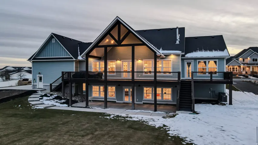 Snow covered property featuring stairway, a deck, a patio area, and board and batten siding