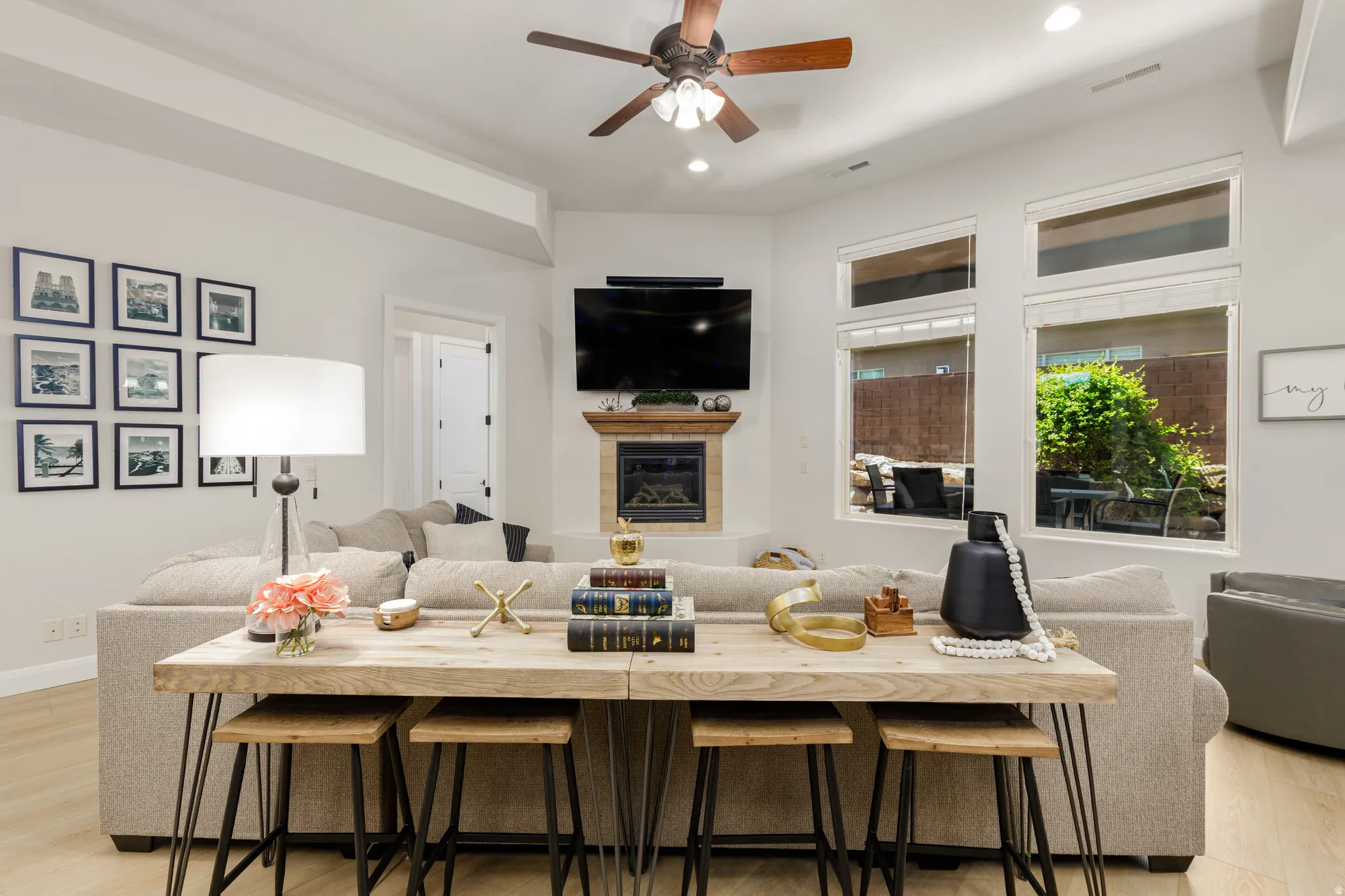 Living room featuring light wood-style floors, a fireplace, ceiling fan, and recessed lighting