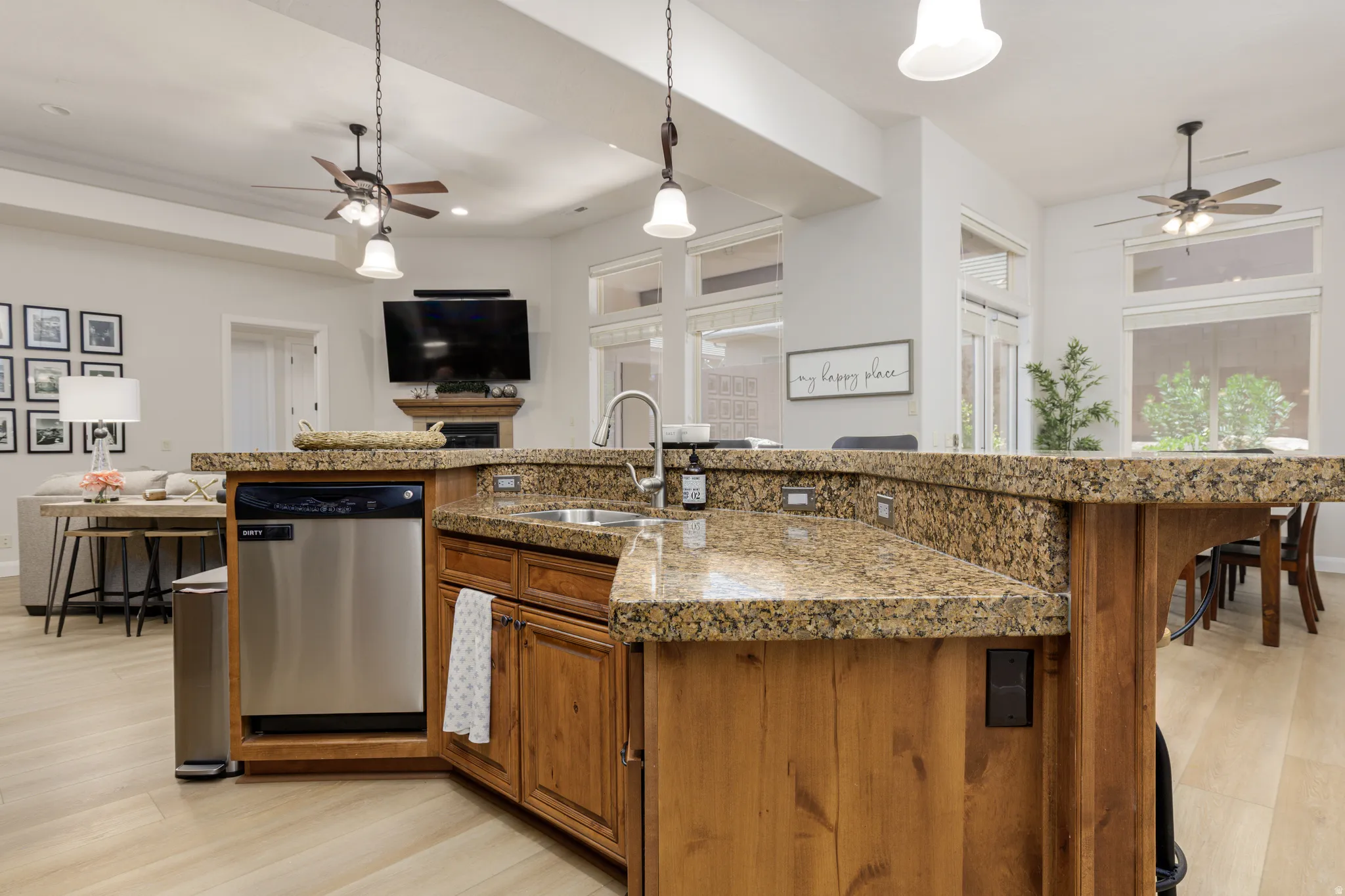 Kitchen with a ceiling fan, wood finish cabinets, light wood-type flooring, and stainless steel dishwasher