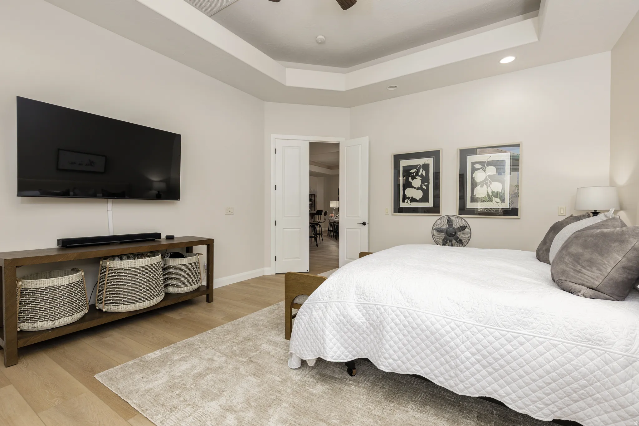 Bedroom featuring light wood-type flooring, a tray ceiling, and a ceiling fan