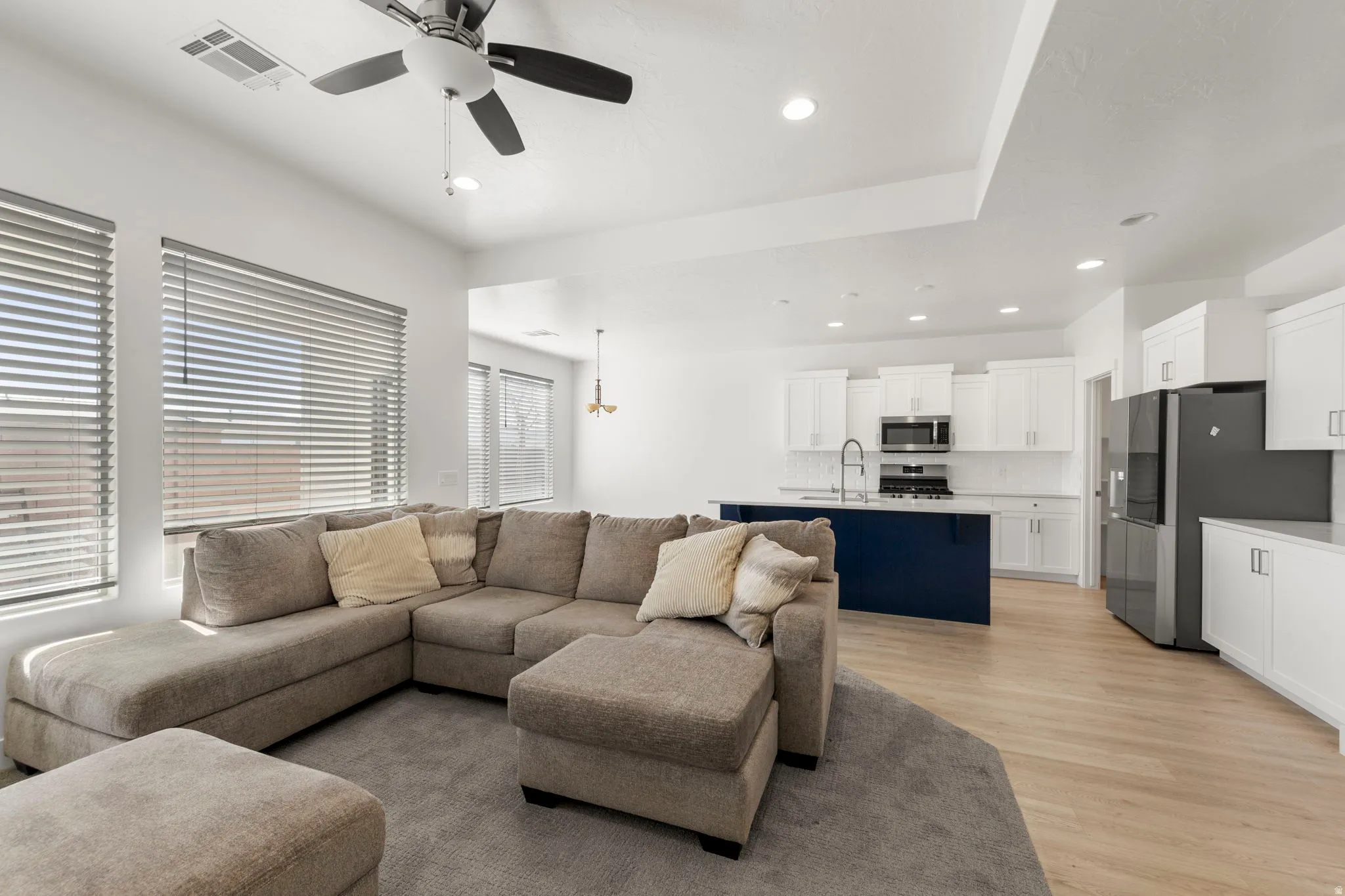 Living area with light wood-type flooring, a ceiling fan, and recessed lighting
