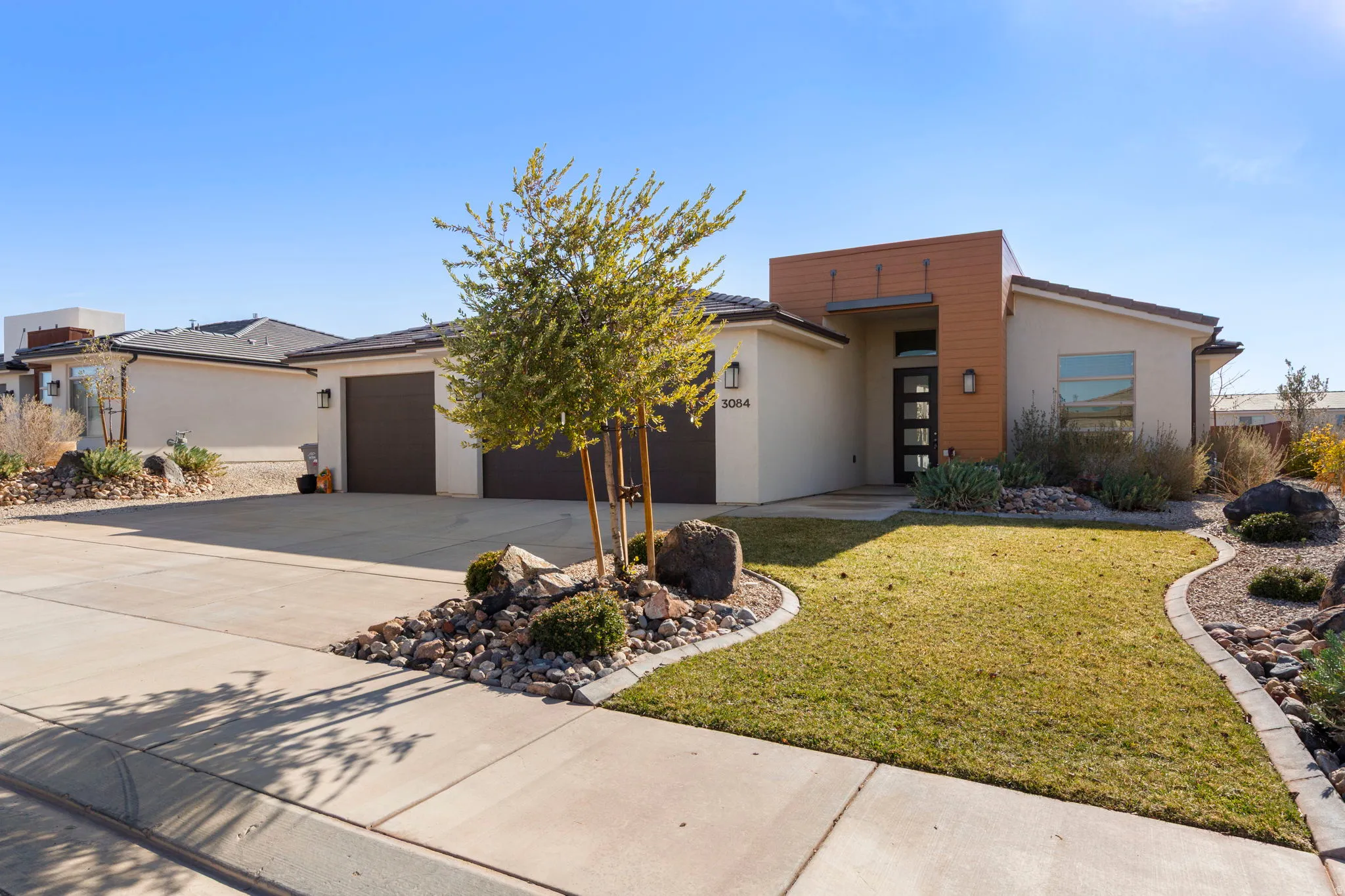 View of front of property featuring a front yard, stucco siding, driveway, and a garage