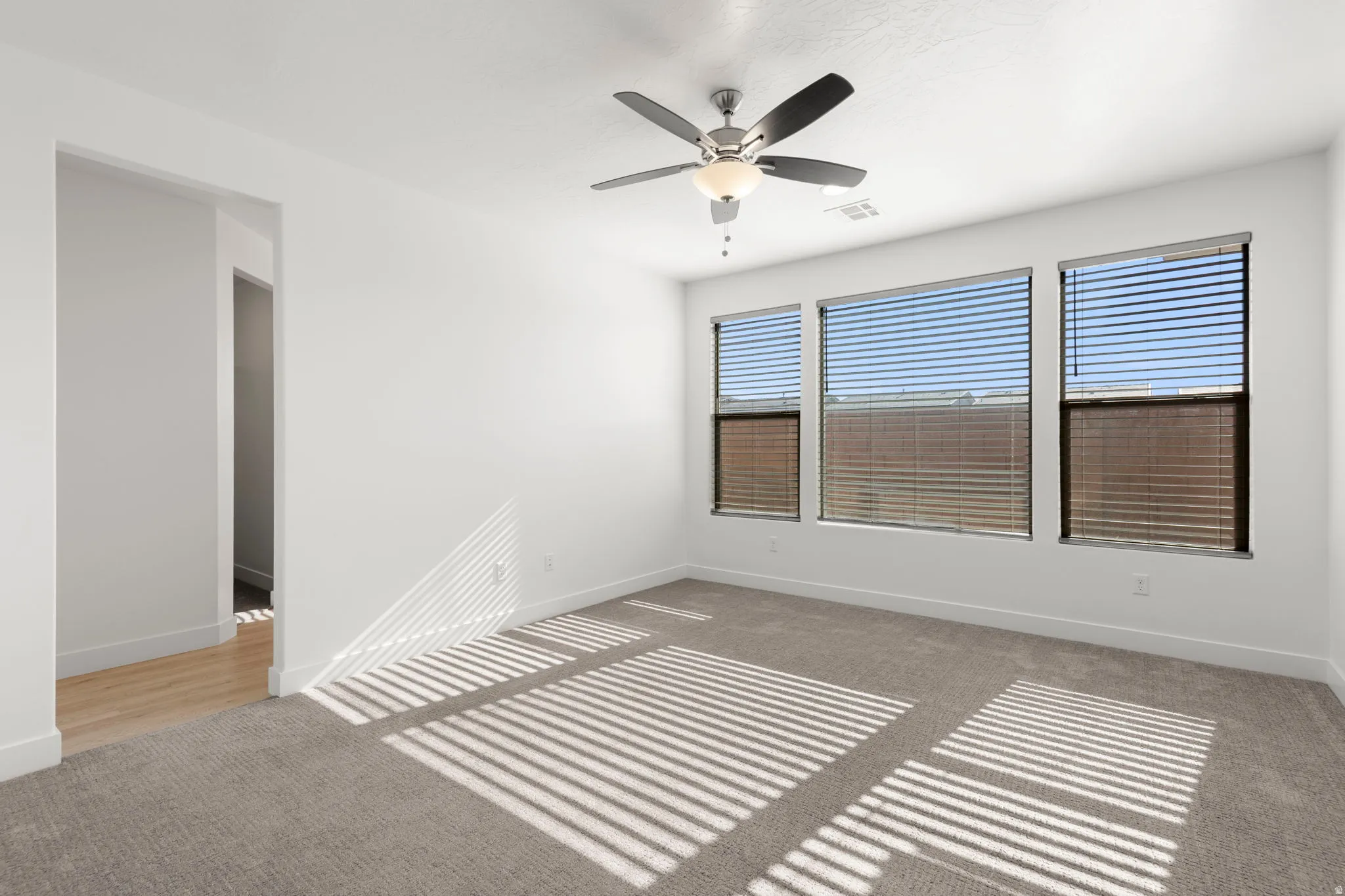 Unfurnished room with light colored carpet and a ceiling fan