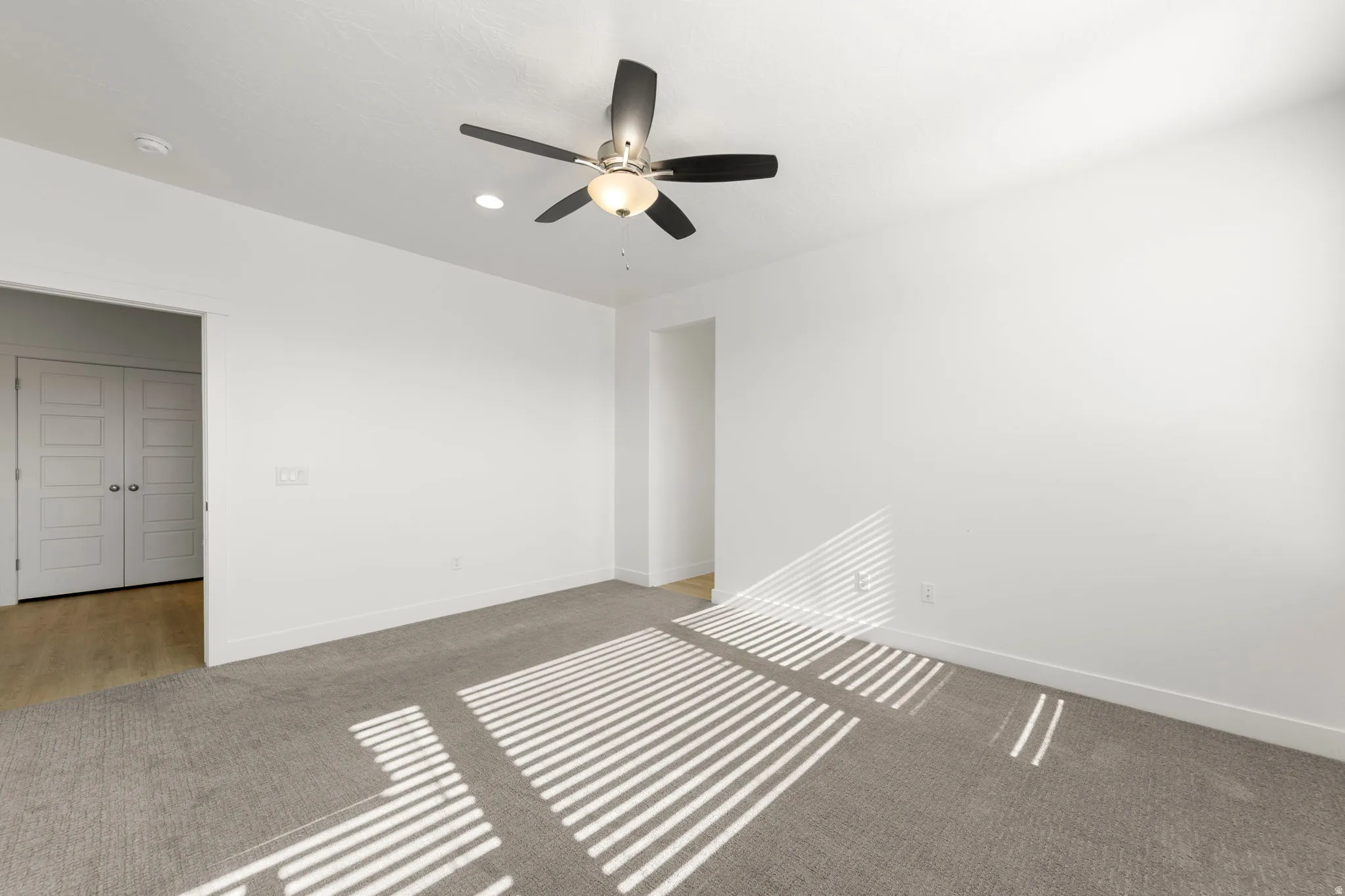 Carpeted spare room with baseboards and ceiling fan