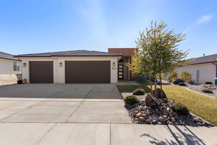 View of front of home featuring concrete driveway, an attached garage, stucco siding, and a front lawn