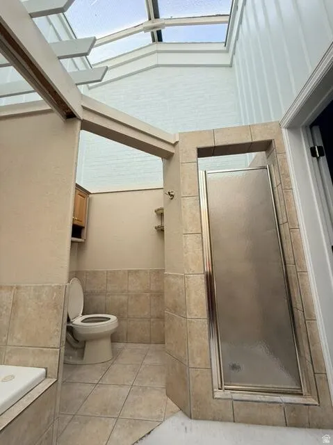 Full bathroom featuring a shower stall, light tile patterned flooring, and plenty of natural light