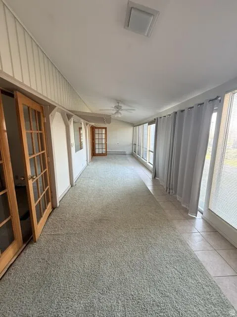 Unfurnished room featuring light tile patterned flooring, french doors, a ceiling fan, and light colored carpet