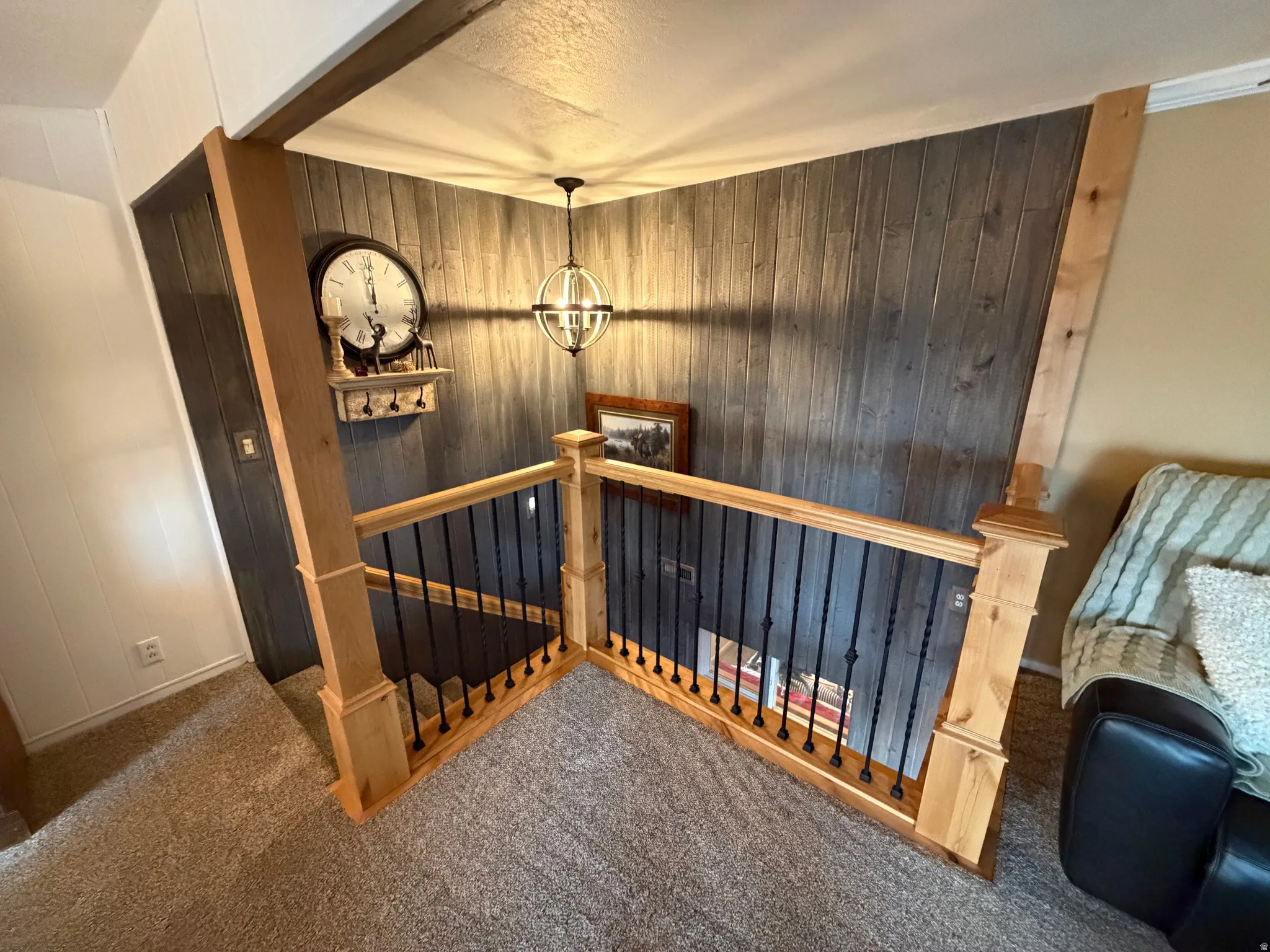 Stairs with carpet flooring, a textured ceiling, a chandelier, and wood walls