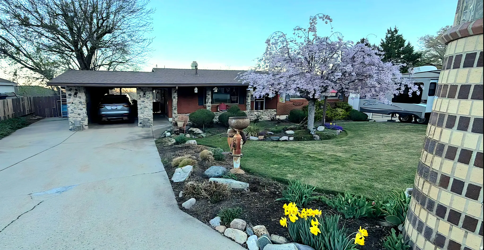 View of front facade with a front yard, a carport, concrete driveway, and covered porch